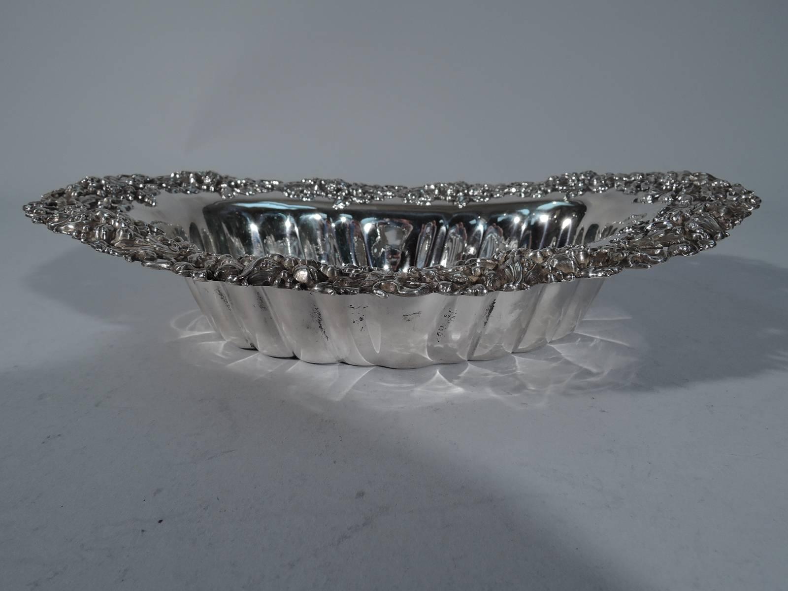 Sterling silver serving bowl. Made by Mauser in New York, circa 1890. Oval and lobed bowl with fancy floral rim abounding in pierced blossoms and seed-bursting vegetation. Interlaced script monogram engraved in well. Hallmark includes 55014. Very