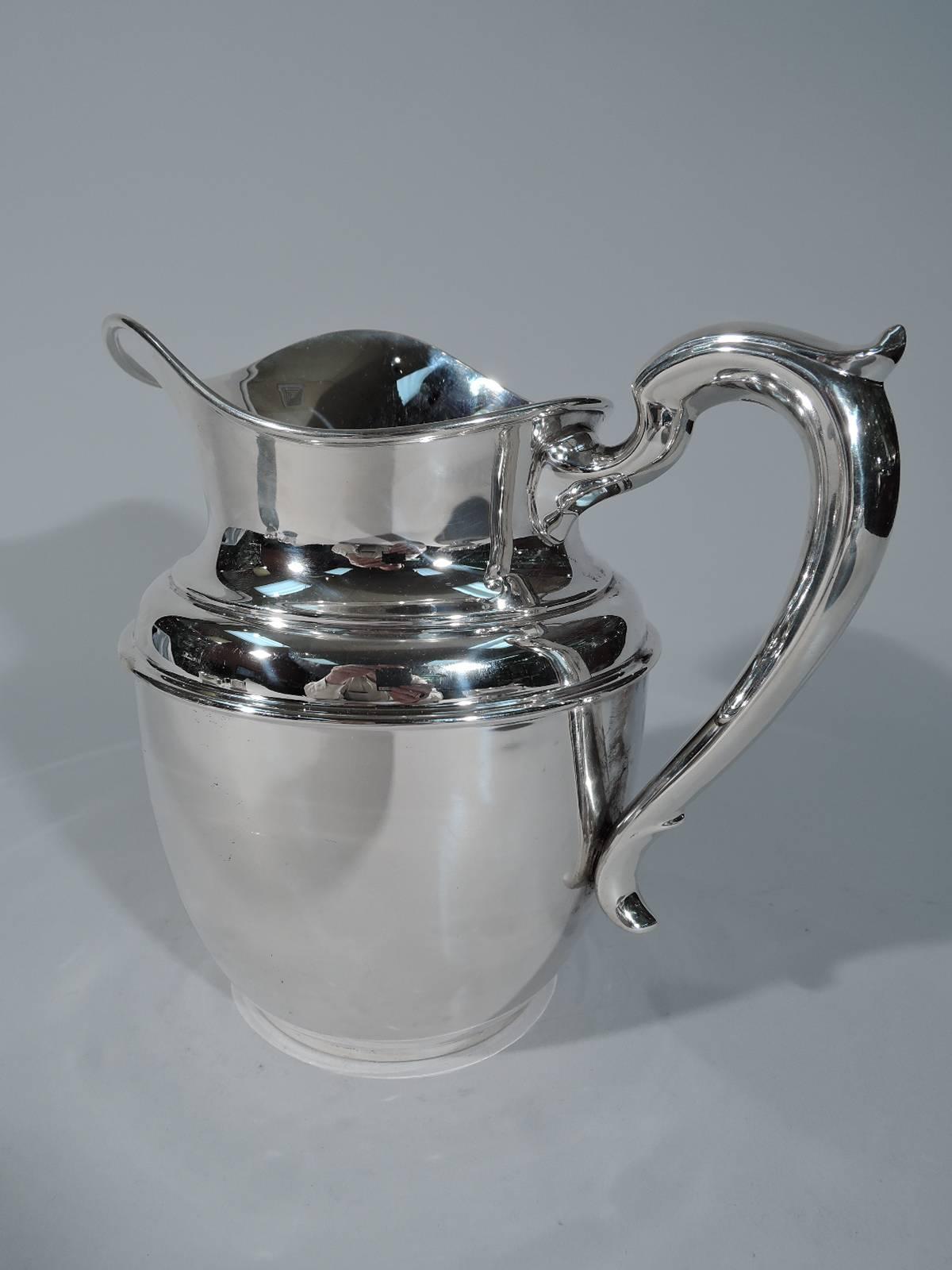 Clean-looking sterling silver water pitcher. Retailed by Tiffany & Co. in New York, circa 1920. Bulbous body with helmet mouth and capped scroll handle. Hallmark includes no. 980. Very good condition. Dimensions: H 7 3/8 x W 8 3/8 x D 6 in. Heavy