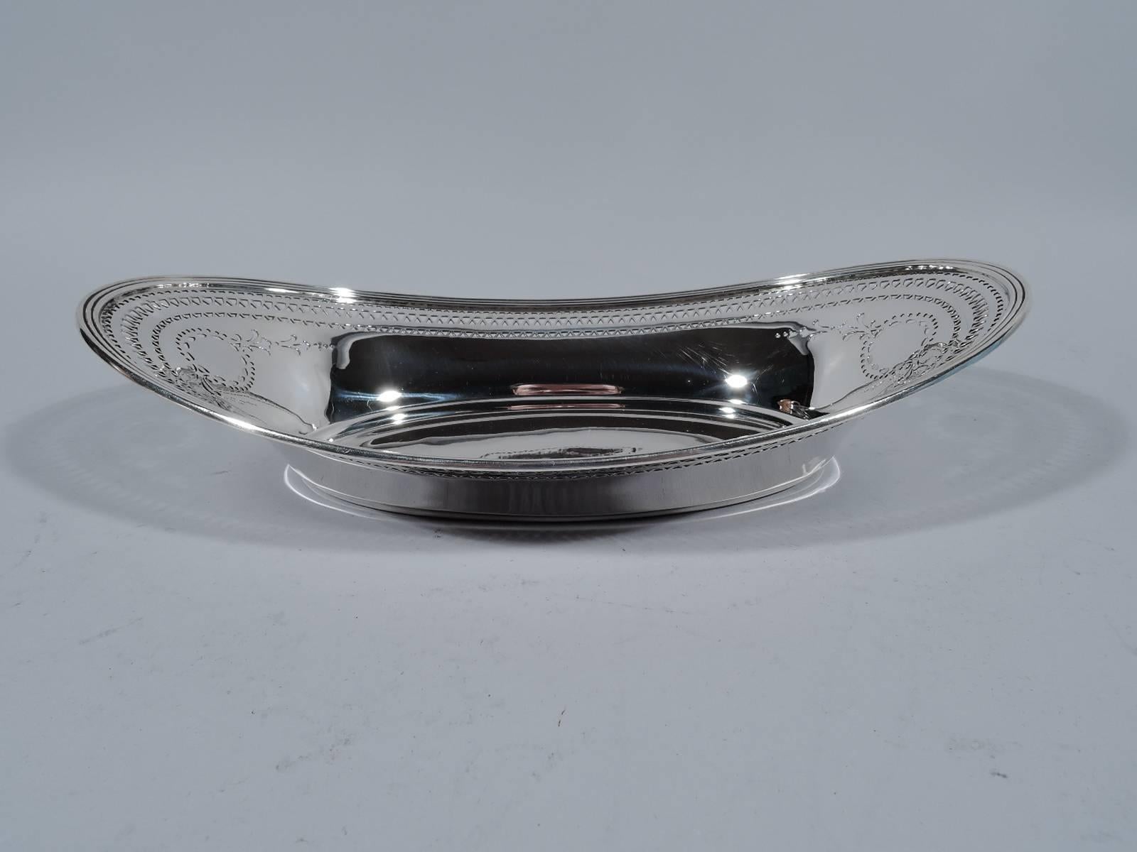 Edwardian sterling silver bread tray. Made by Tiffany & Co. in New York, circa 1912. Oval well with tapering sides and reeded and asymmetrical rim. Pierced borders and garland-supported wreaths (vacant). Hallmark includes pattern no. 18197B (first