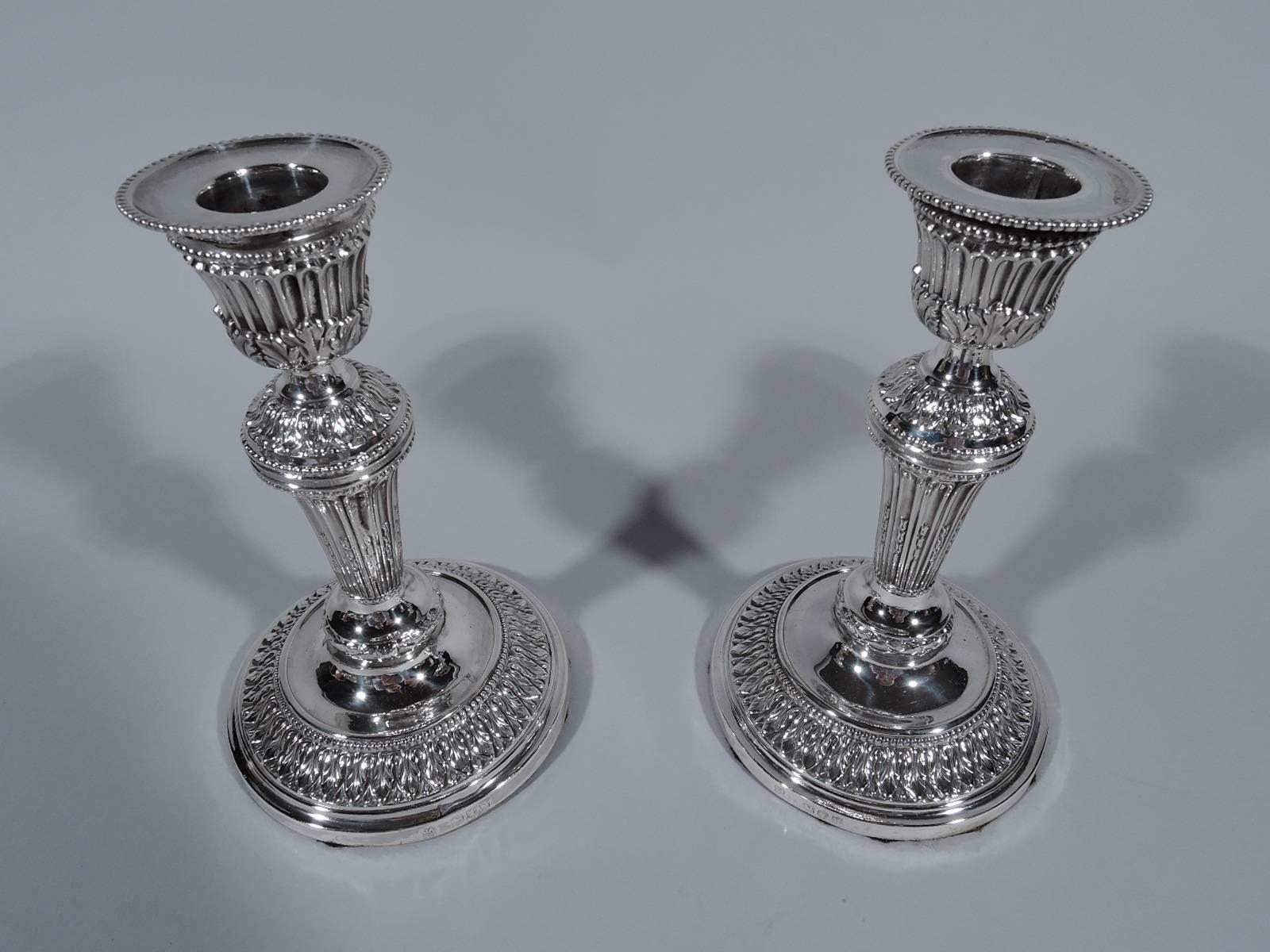 Pair of Victorian sterling silver candlesticks. Made by John Aldwinckle & Thomas Slater in London, 1892-1893. Each: Tapering column on raised foot. Detachable bobeche. Neoclassical ornament including beading, leaf-and-dart, and acanthus leaves. A