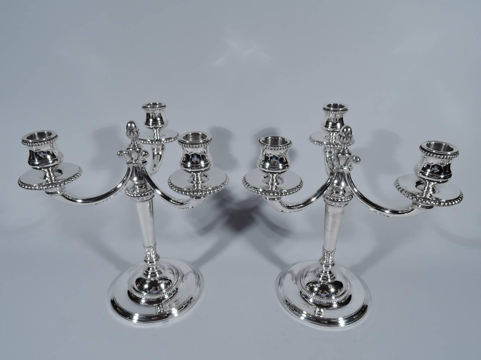 Pair of Three-light candelabra in 950 silver. Made by Robert Linzeler in Paris, circa 1920, for Cartier. Each: tapering shaft with stylized leaves and knop on dome base mounted to raised foot. Three tapering C-scroll arms, each with volute scroll