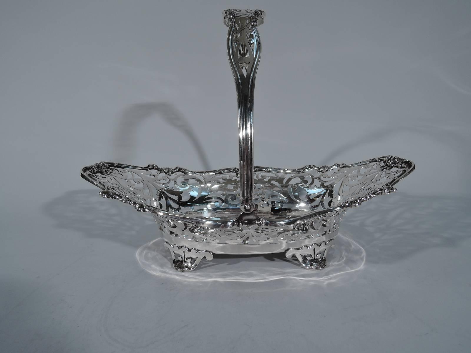 Edwardian sterling silver basket. Made by Wilcox & Wagoner (later Watson) in New York, circa 1900. Solid oval well. Flared and asymmetrical sides with bold pierced and stylized scrolls and leaves. Rim comprises joined scrolls with pretty flowers.