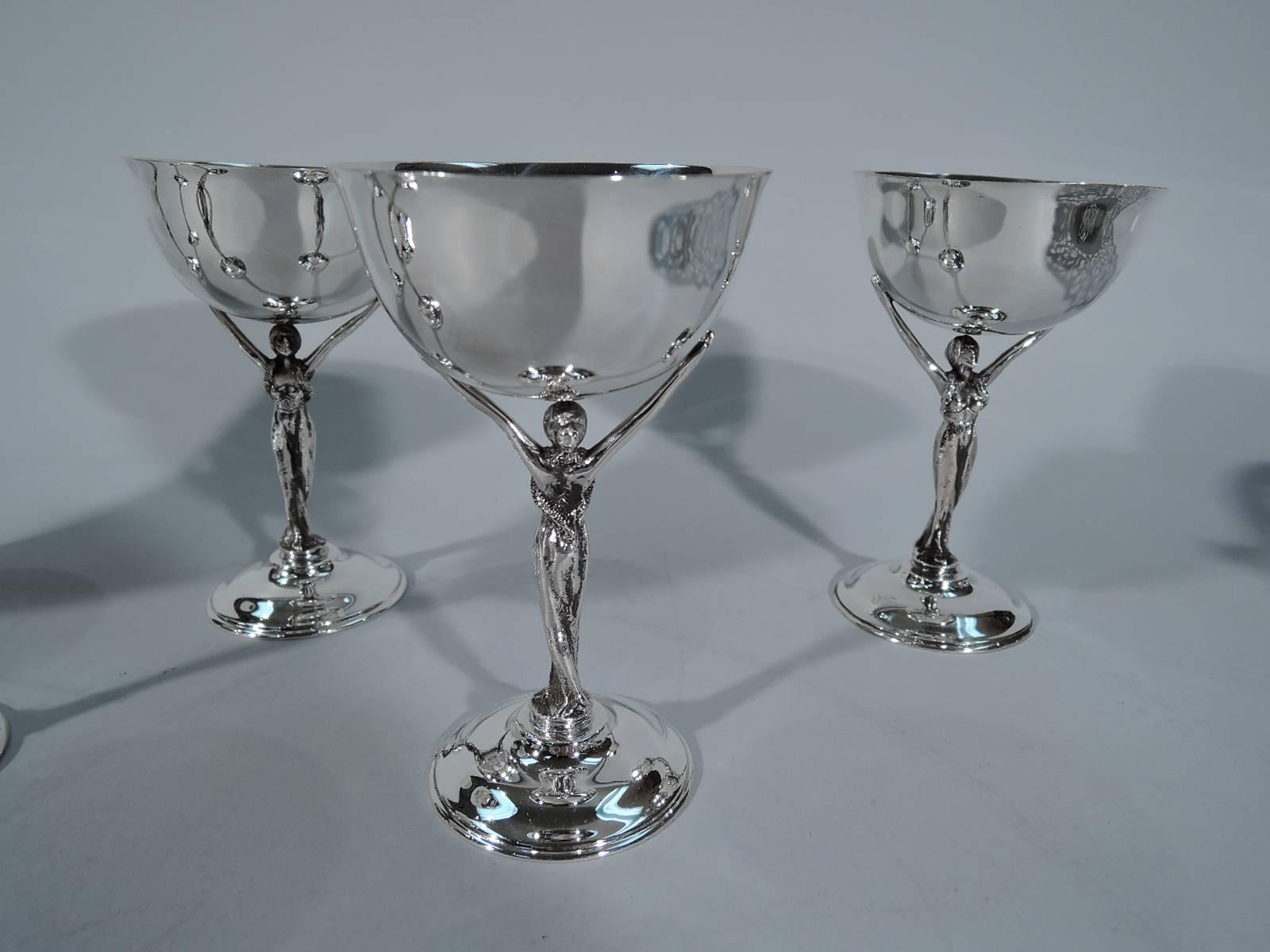Set of six sterling silver cocktail glasses. Retailed by Udall & Ballou in New York, circa 1920. Each: A glamorous girl in clingy sheath stands on raised base and supports with raised arms a curved bowl. An inspired adaption of Classicism to Jazz
