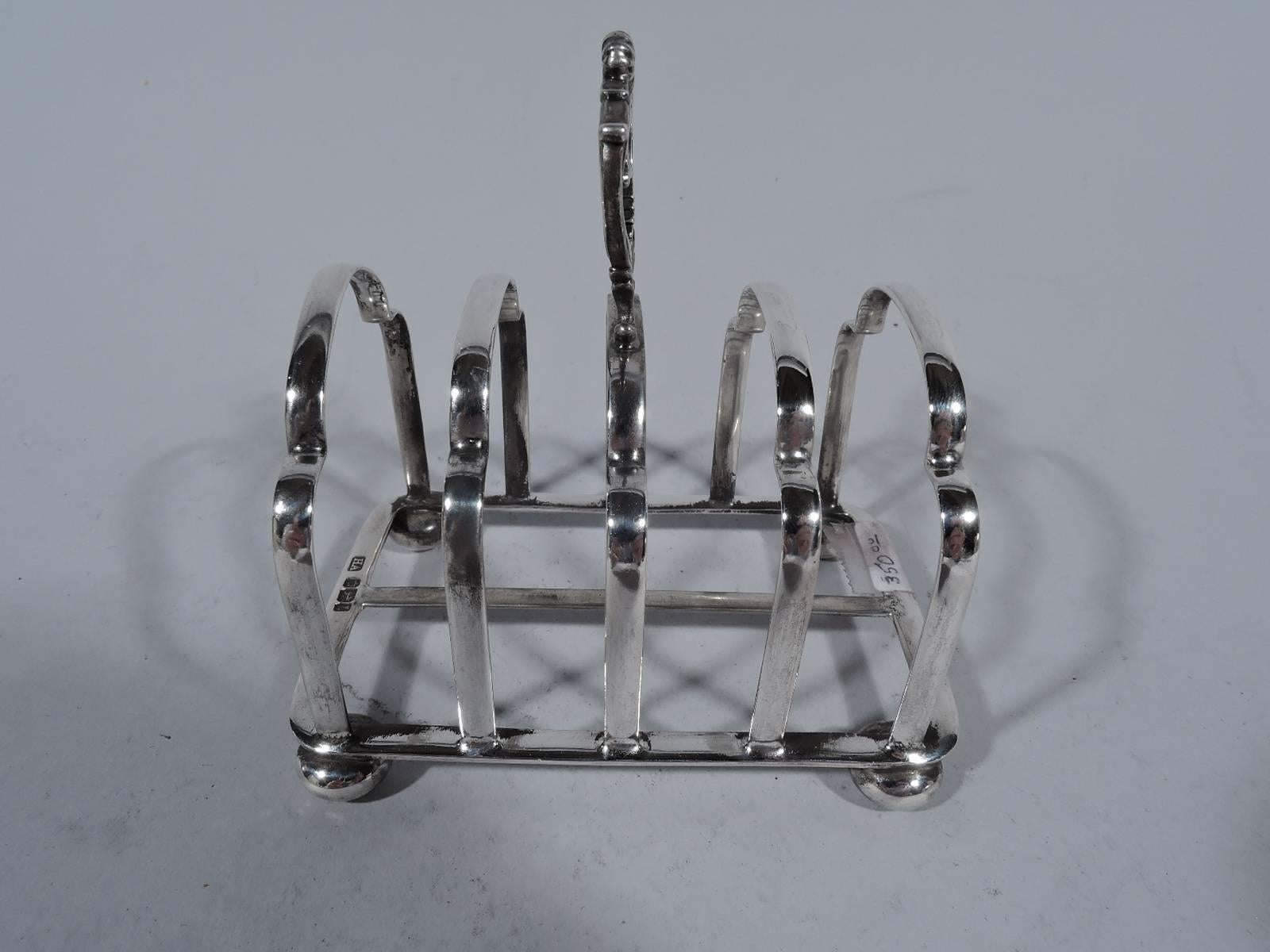 Edwardian sterling silver toast rack. Made by Atkin Brothers in Sheffield in 1903. Five trefoil arches mounted to rectangular frame with stretcher on 4 bun supports. Handle comprises 2 joined scrolls. A practical addition to the breakfast tray.