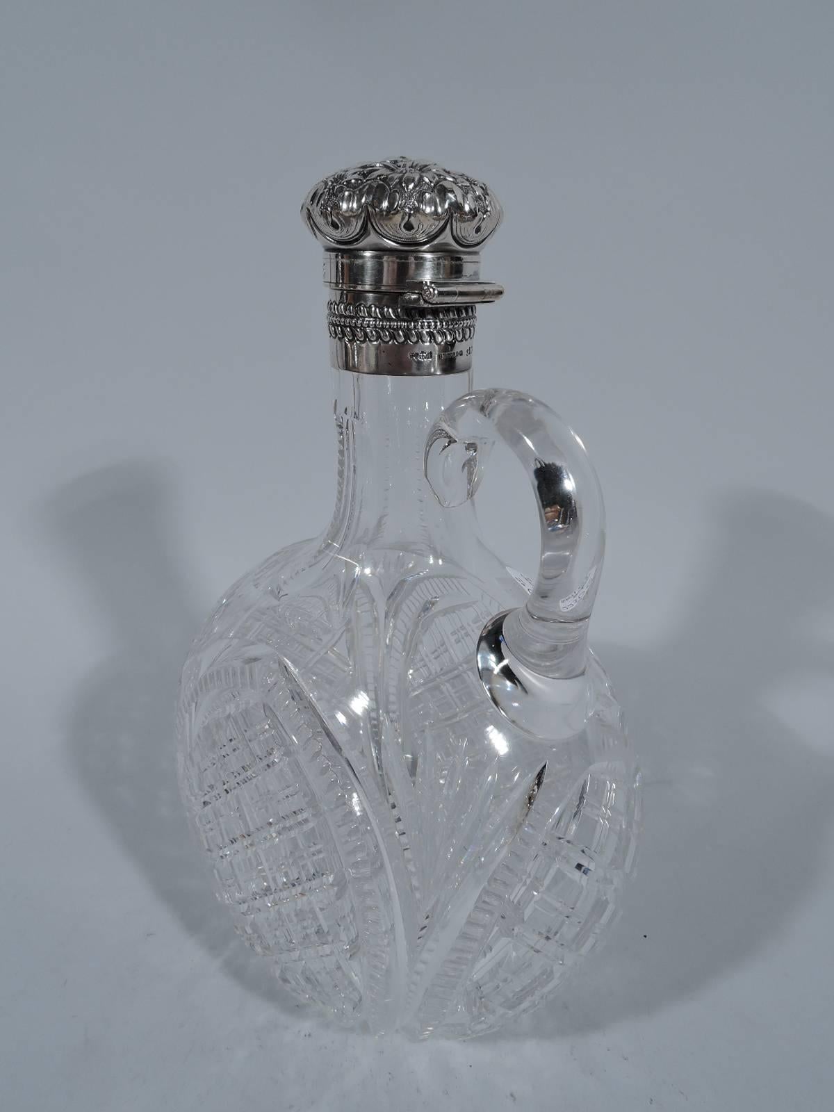 Brilliant-cut-glass and sterling silver decanter. Made by Gorham in Providence in 1894. Round body with thumb ring handle. Cut ornament in arched frames. Collar silver as is hinged and cork-lined cover with floral repousse. On cover is engraved