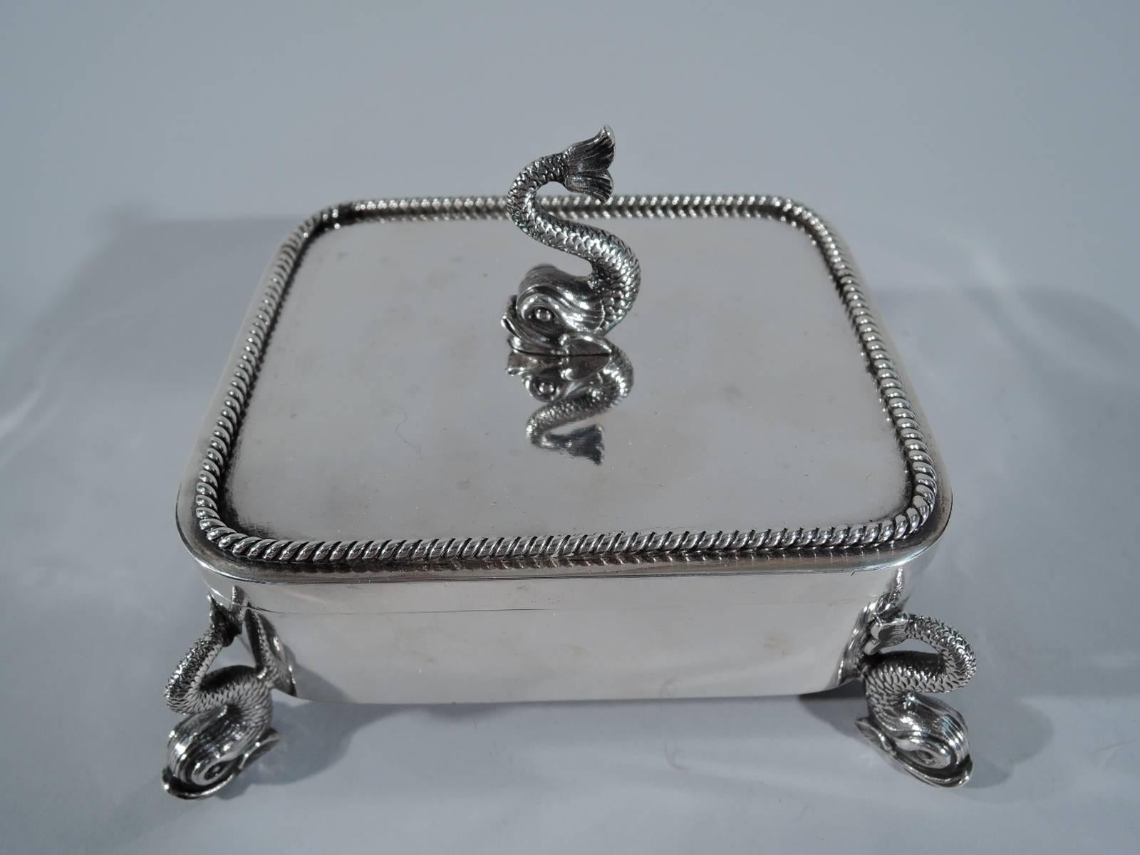 Rare sterling silver desk box. Made by Tiffany & Co. in New York, circa 1865. Rectangular with straight sides and curved corners. Flat cover with applied cable border. Corner supports and finial in form of cast dolphin figures. A restrained design