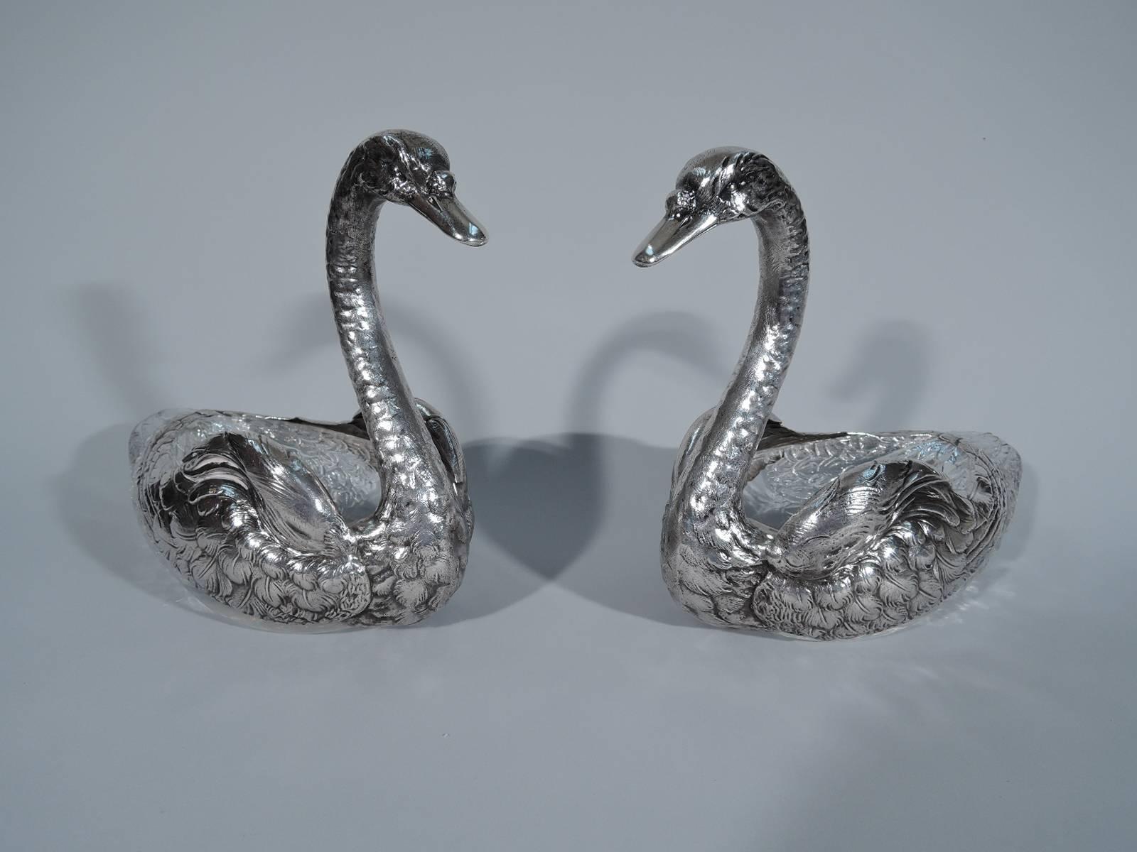Pair of large American sterling silver and glass swans, circa 1900. Each cut-glass body mounted with silver wings, neck, and head. Finely delineated plumage. Neck and head shapely with closed bill and beady eyes. Hollow for holding
flowers or
