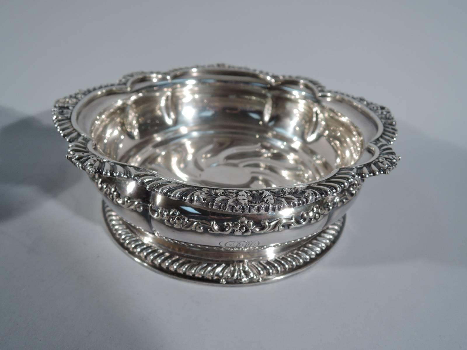 Pair of silver plate wine bottle coasters. Made by Tiffany & Co. in New York, circa 1890. Each: Lobed sides with flat rim comprising alternating large and small scallops. Rim gadrooned and decorated with shells and leaves. Bottom has twisted