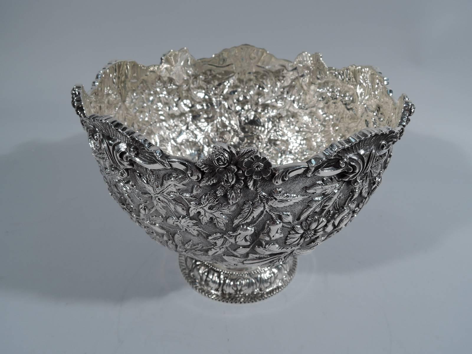 Beautiful sterling silver bowl. Made by S. Kirk & Son Co. in Baltimore in early 20th century. Deep and round bowl with floral repousse in form of scattered blossoms on stippled ground. Asymmetrical rim with alternating leaves and posies. Raised foot