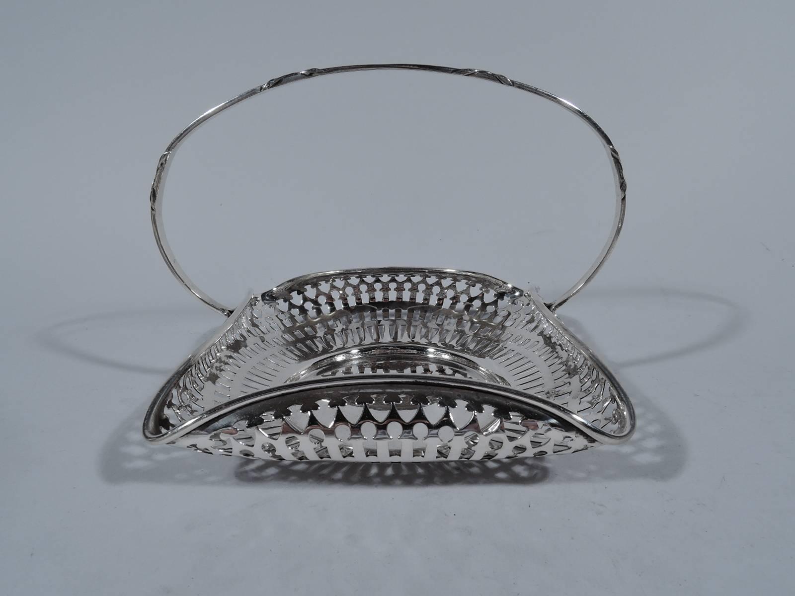 Edwardian sterling silver basket. Made by Gorham in Providence in 1916. Solid circular well and 4 curved sides with turned-in molded rim. Concentric geometric piercing. Stationary C-scroll reeded handle. Hallmark includes no. A7984 and date symbol.