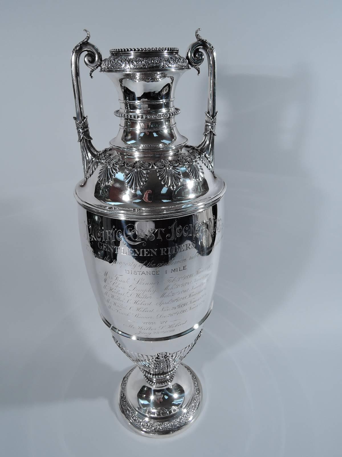Sterling silver horse racing trophy. Made by Tiffany & Co. in New York, circa 1889. Amphora with tall body on raised foot. Two-leaf capped straight handles with leaf mounted to shoulder and volute scroll terminal mounted to neck. Ornament includes