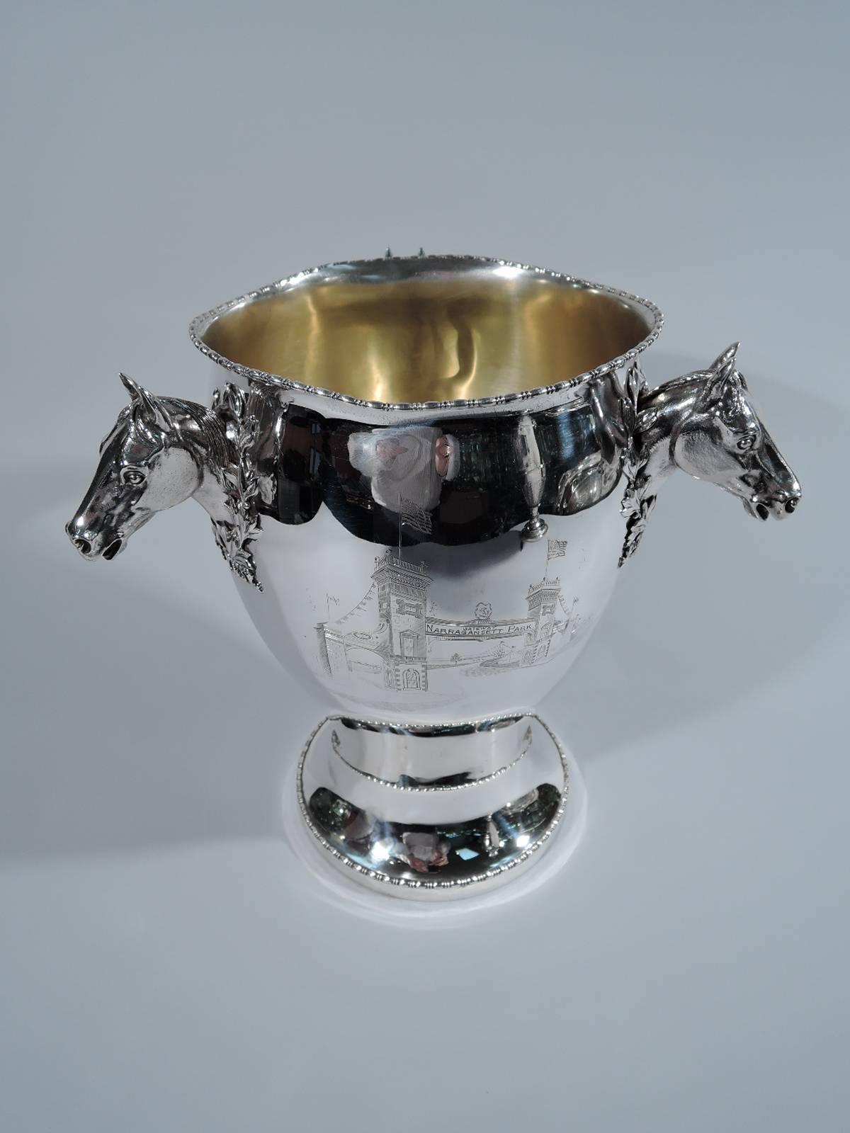 American sterling silver trophy cup. Baluster body with three cast horse heads, each wearing a winner’s wreath. Bead-and-reel ornament on rim and foot.
Pictorial engraving of Narragansett Park Gateway. Also: “Free for all trot to wagon won by
