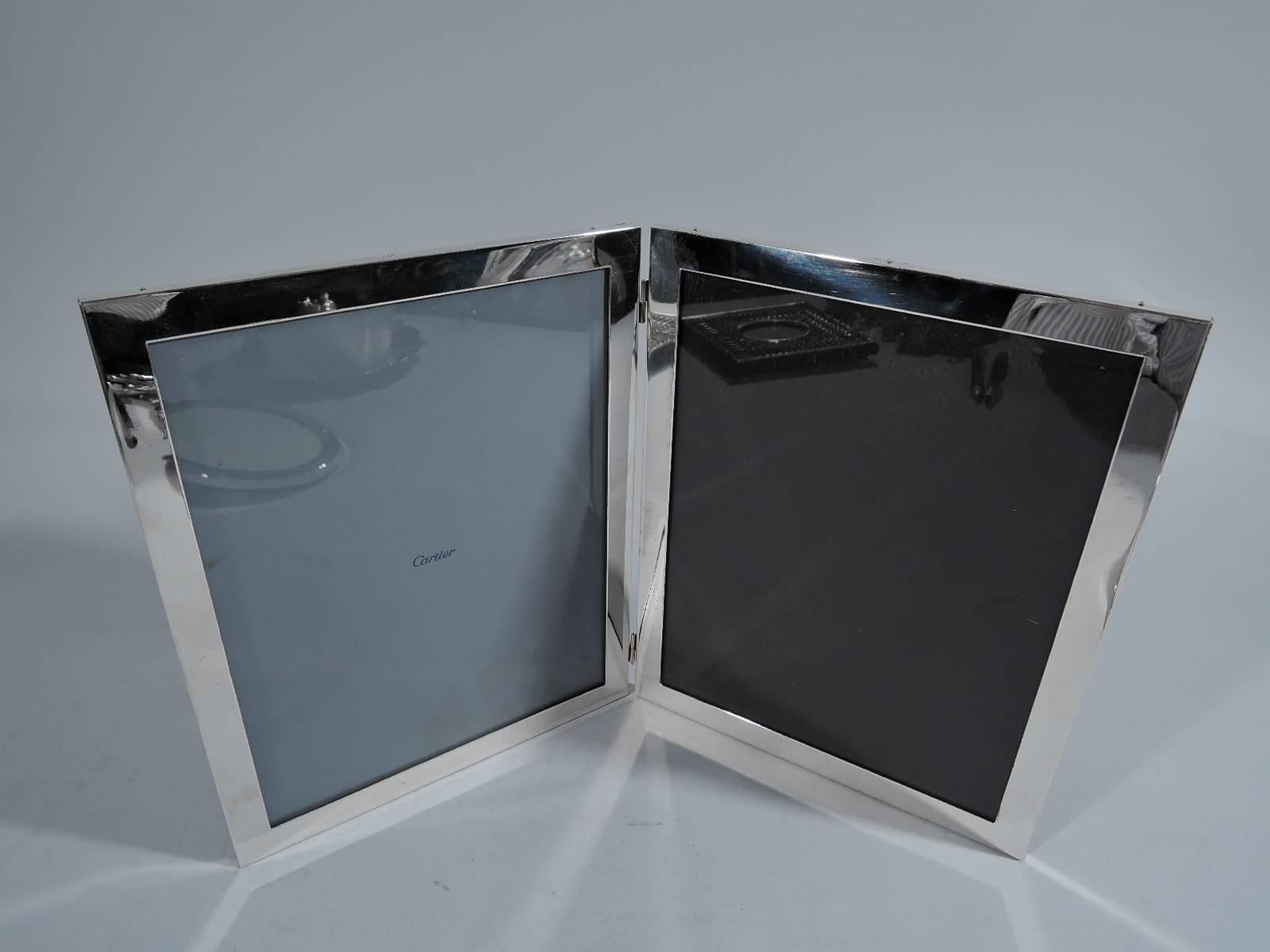 American sterling silver diptych. Two hinged frames, each with flat border, glass and leather back. Hallmarked Raimond, a Massachusetts maker active in the 1960s and 1970s. One window has retailer’s liner for Cartier. 

Dimensions: Each frame 10