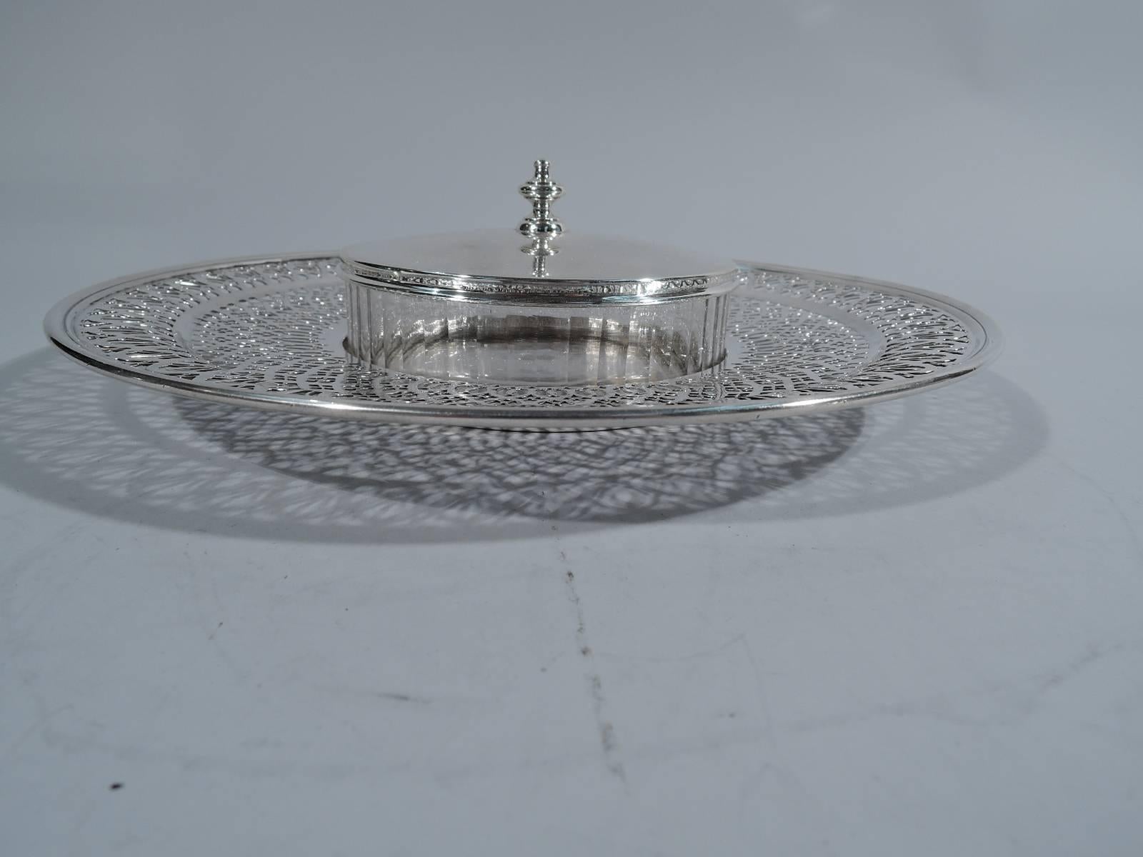 Edwardian sterling silver and glass dish on plate. Made by Tiffany & Co. in New York, circa 1914. Dish is clear glass with impressed lobes. Cover silver and slightly raised with finial. Plate is silver with solid well and wide rim with pierced