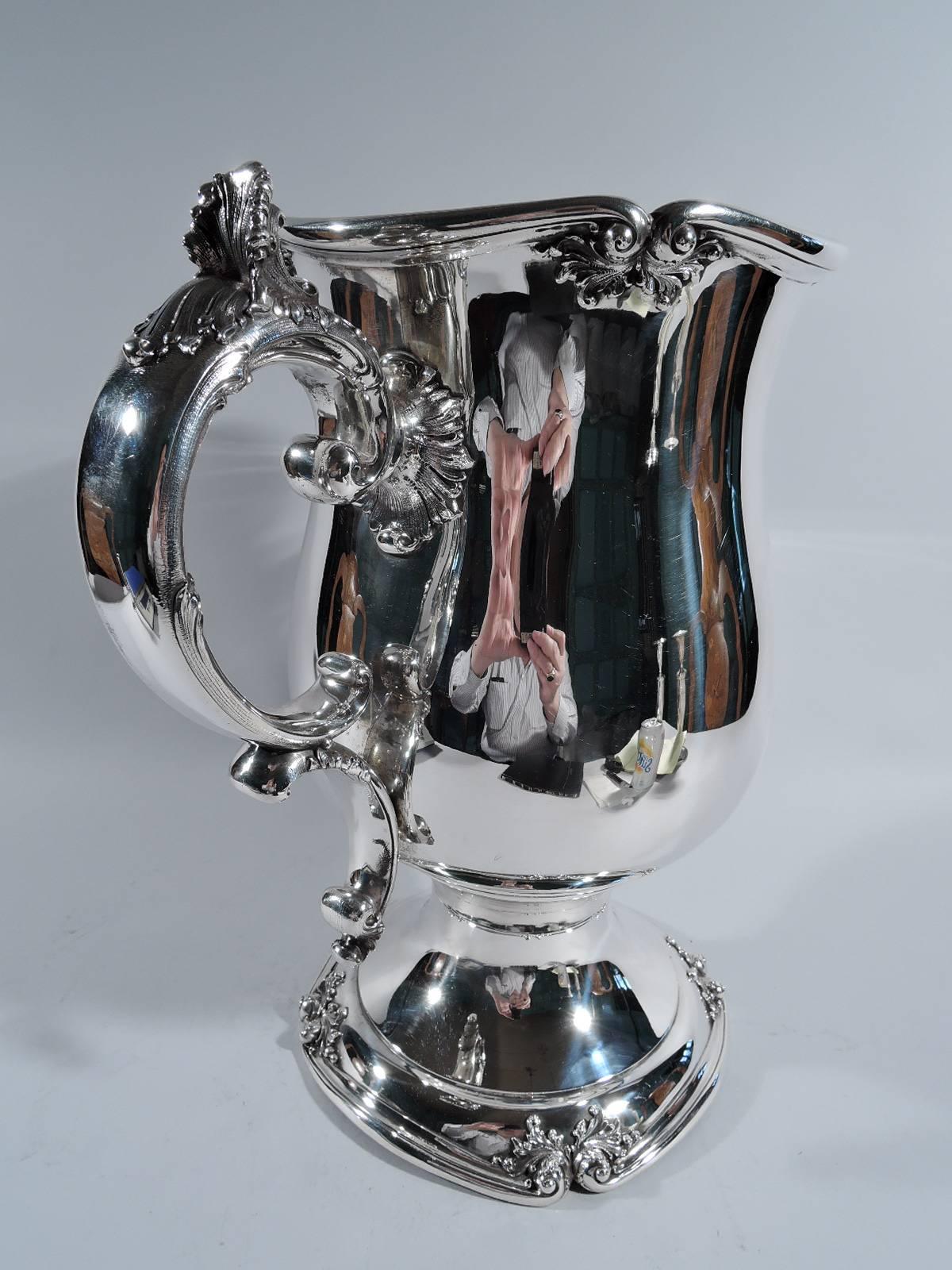 Sterling silver trophy Cup. Made by Meriden Britannia (part of International) in Meriden, Conn., circa 1890. Urn form with leaf-capped double-scroll handles and wavy rim with volute scrolls and applied leaves. Raised foot has four curved sides with