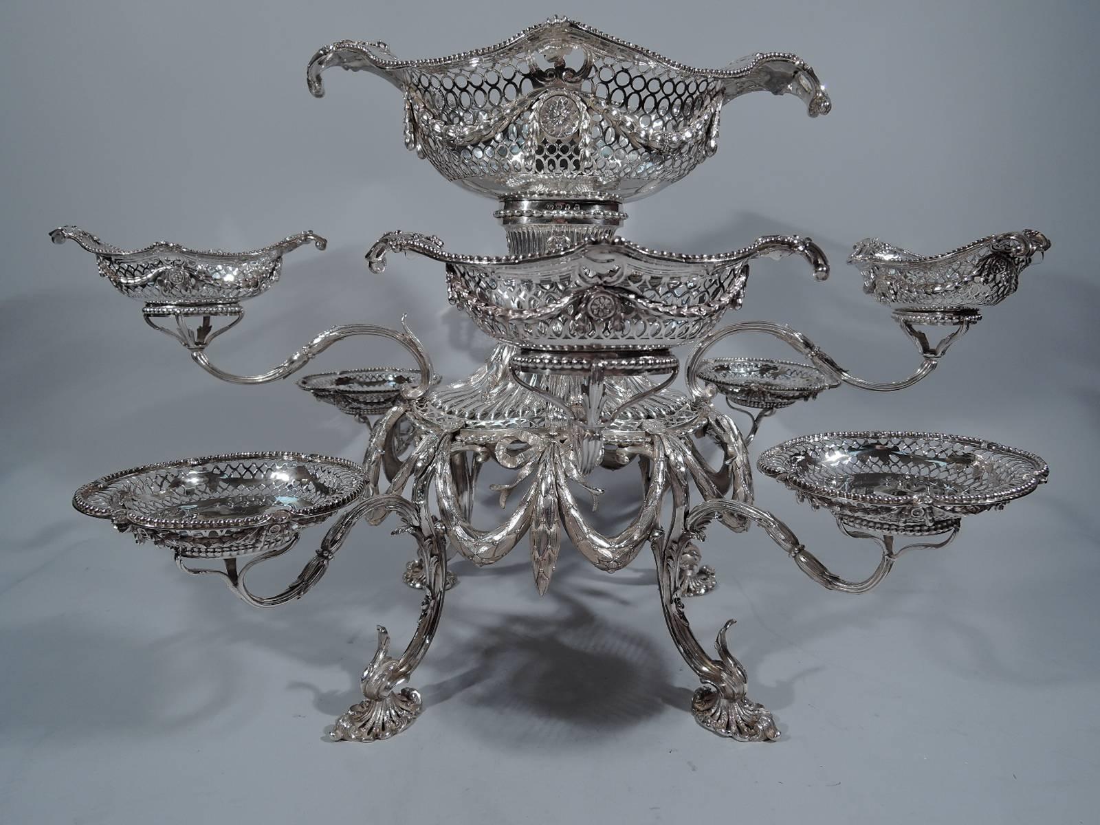 George III sterling silver epergne. Made by Thomas Pitts in London in 1771. Large oval basket on gadrooned shaft with pierced oval border and ribbon-tied laurel swags on four-leaf capped and scrolled supports. Eight branches, terminating in