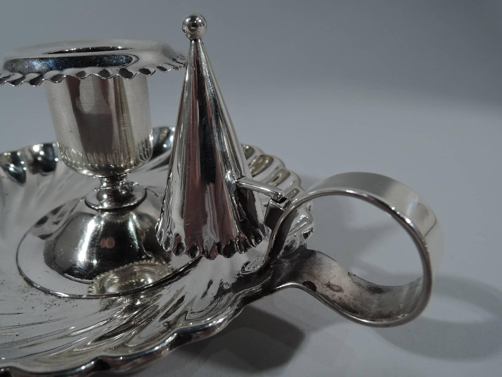 Sterling silver chamberstick. Made by Tiffany & Co. in New York, circa 1894. Urn socket on mounted to raised foot. Tray has curved sides with twisted fluting and scalloped rim. Plain ring handle with snuffer support. Snuffer conical with bead finial