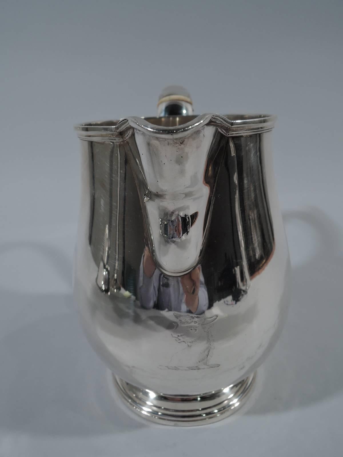 George III sterling silver water pitcher. Made by John Edwards III and Edward Edwards in London in 1811. Curved body on stepped foot. V-spout and capped scroll handle. Engraved armorial. On foot underside is engraved presentation dated 1908. Good