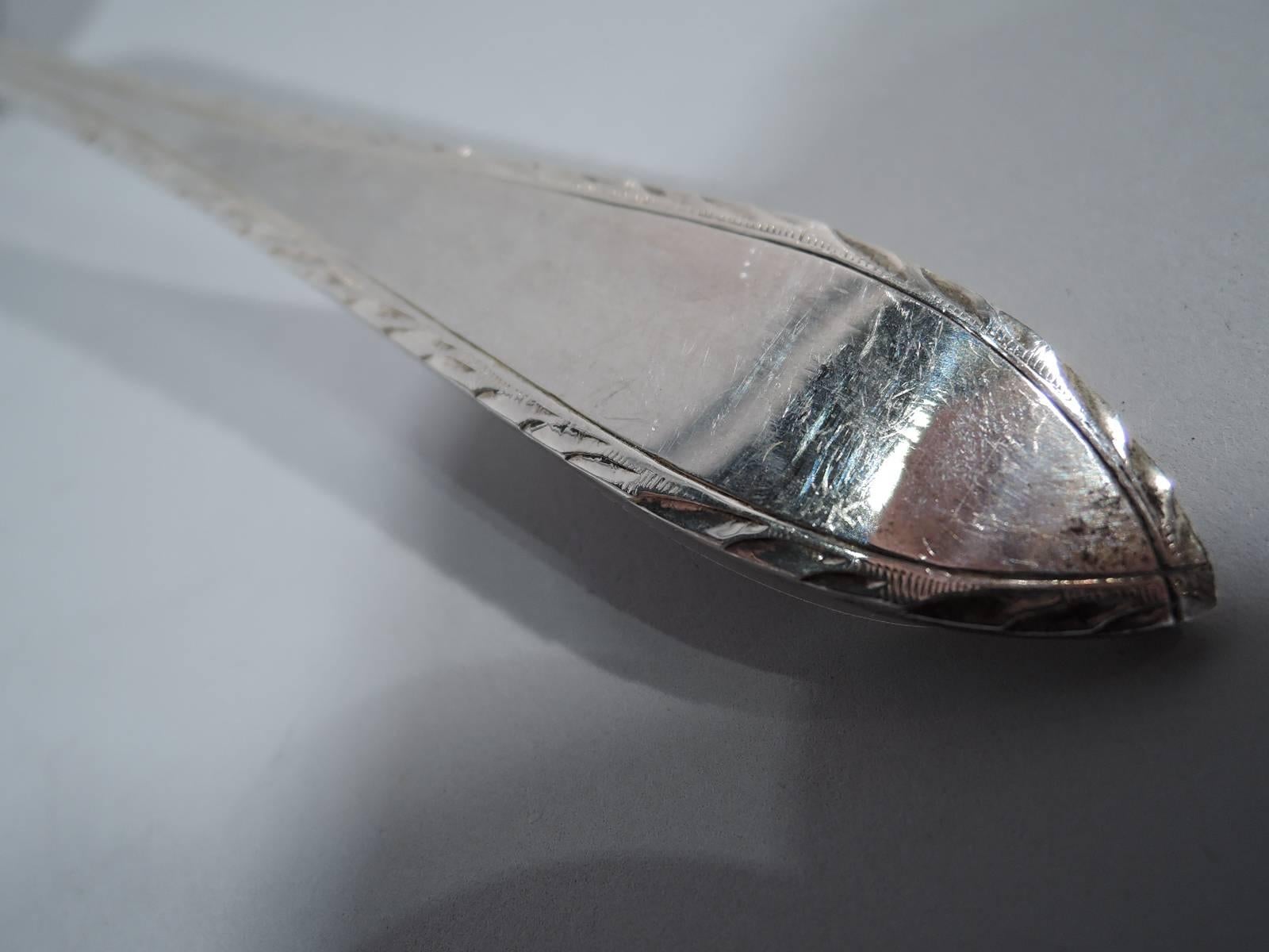 Antique sterling silver serving spoon in Feather Edge pattern. Made by Tiffany & Co. in New York. The spoon has a large oval bowl. A Fine piece in this pattern, which was first produced in 1901. Hallmark includes director’s letter m (1907-1947).
