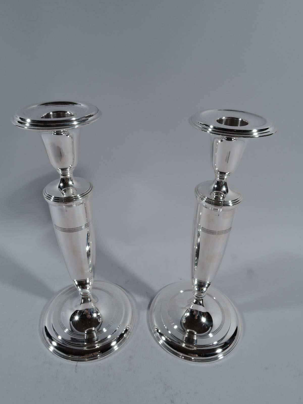 Pair of Classic sterling silver candlesticks. Made by Tiffany & Co. in New York, circa 1922. Tapering shaft on raised foot. Urn socket with detachable bobeche. Reeded bands on shaft and foot. Hallmark includes pattern no. 20132 (first produced in