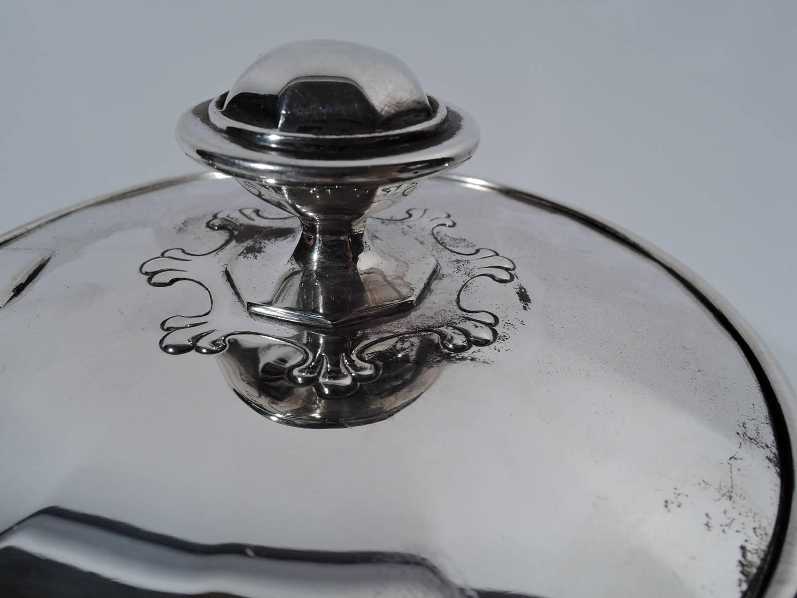 Sterling silver coffeepot in St Dunstan pattern. Made by Tiffany & Co. in New York, circa 1903. Curved and faceted body and s-scroll spout, scroll bracket handle, and raised foot. Cover flat, hinged, and faceted. Fleur de lys (trefoil) ornament. A