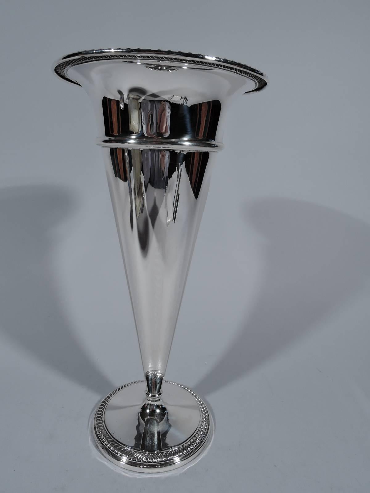 Sterling silver trumpet vase. Made by Fisher in Jersey City, circa 1930. Straight and tapering sides with repousse band and gadrooned and flared rim. Foot circular and gadrooned. Hallmark includes no. 632. Weighted.