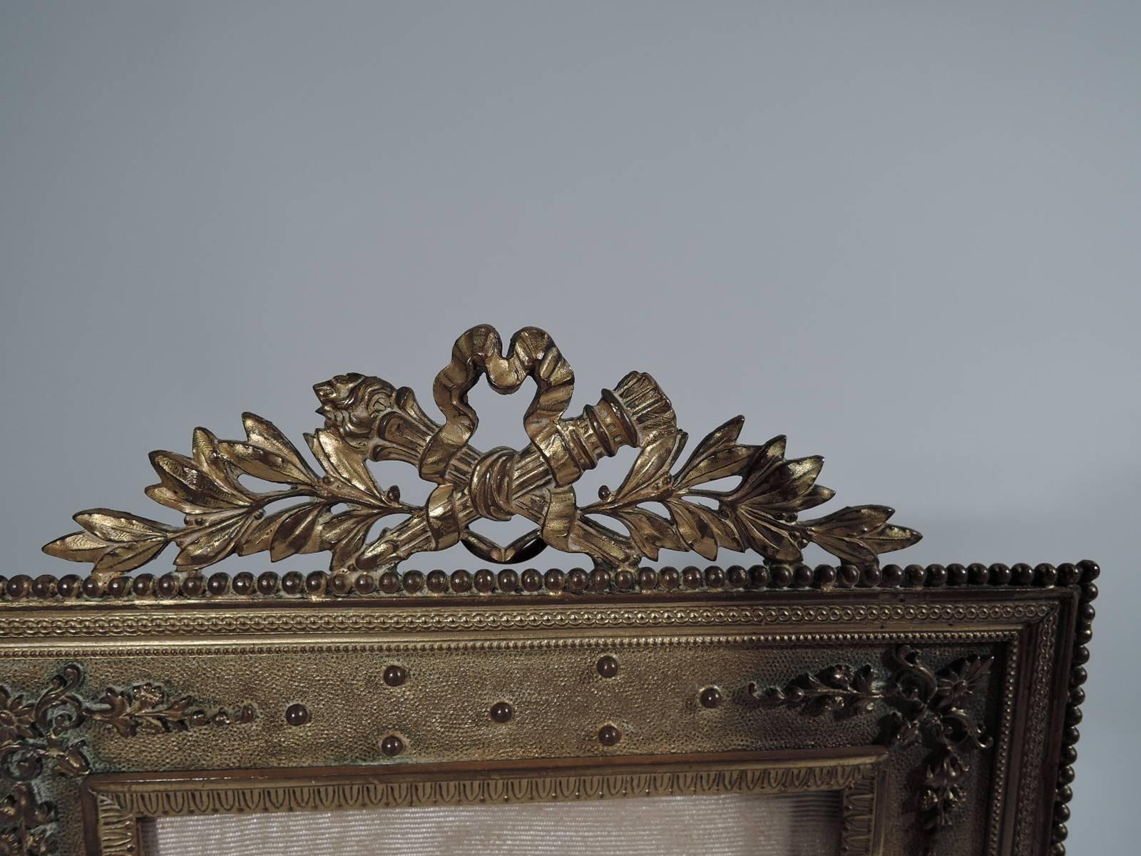 Antique French Rococo Revival gilt bronze picture frame. Rectangular window ornamented with leaf and dart, beading, guilloche, dentil, flowers and leaves. With glass, silk lining and bronze back and hinged support. Retailer’s name “Stern Brothers