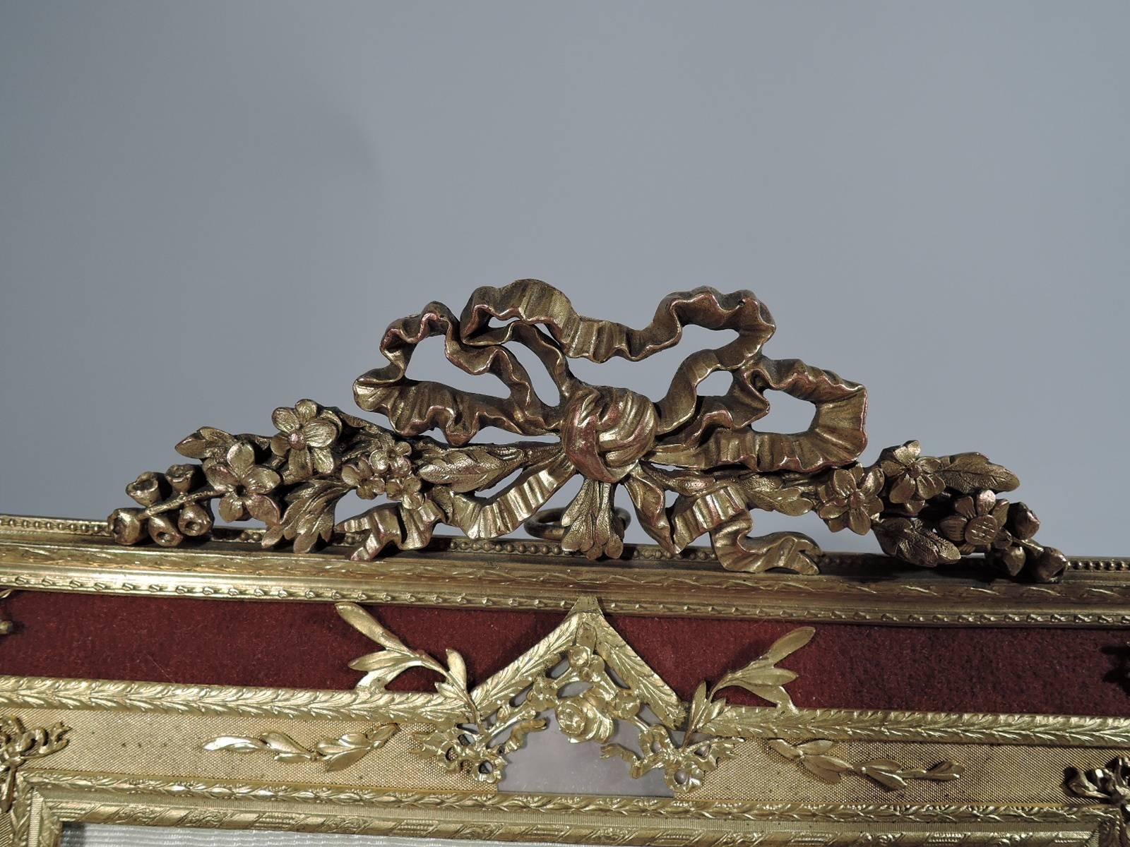 Antique French Rococo revival picture frame. Rectangular window bordered by gilt bronze inset with mother-of-pearl and in turn bordered by dark red (maroon) fabric. Ornament includes beading, flowers, leaves, rinceaux, and paterae. Pierced pediment