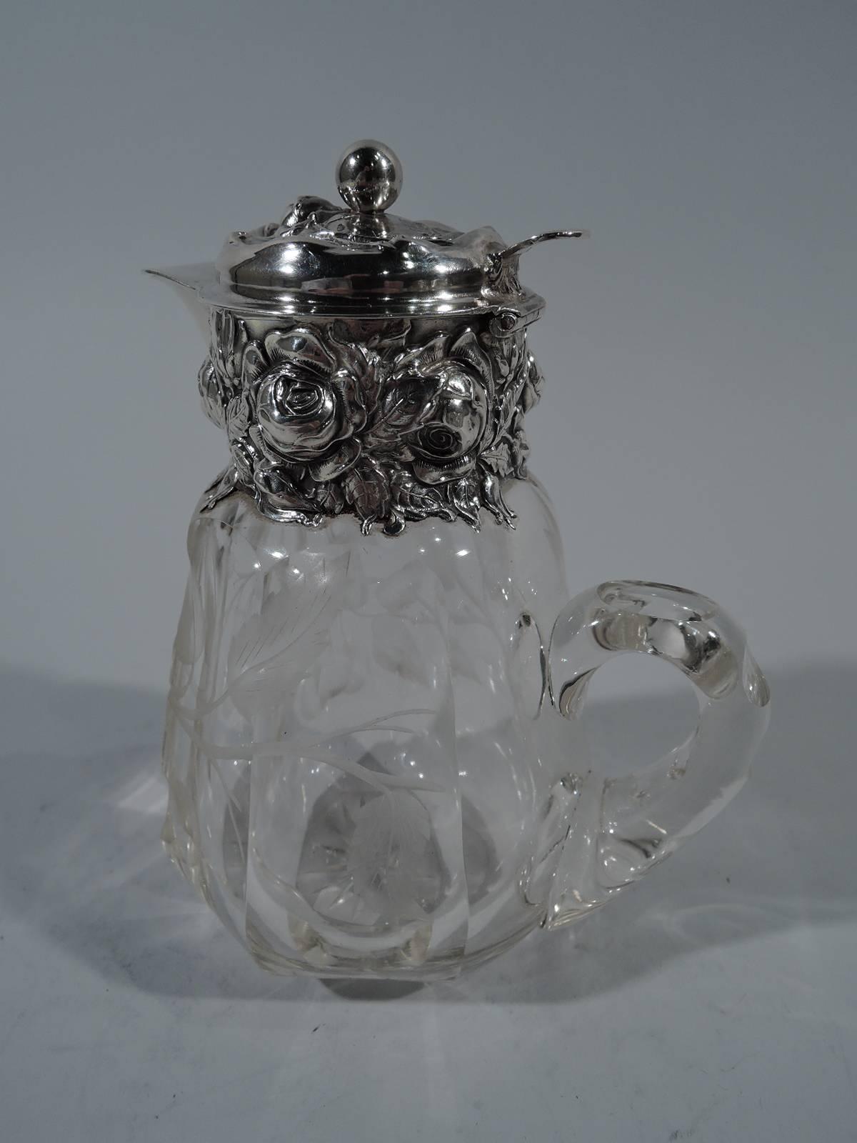 Clear glass syrup jug with sterling silver mounts. Made by Woodside in New York, circa 1900. Faceted body with acid-etched cherry branch. Notched c-scroll handle. Silver collar and hinged cover with floral repousse. Hallmark includes no. 2532.