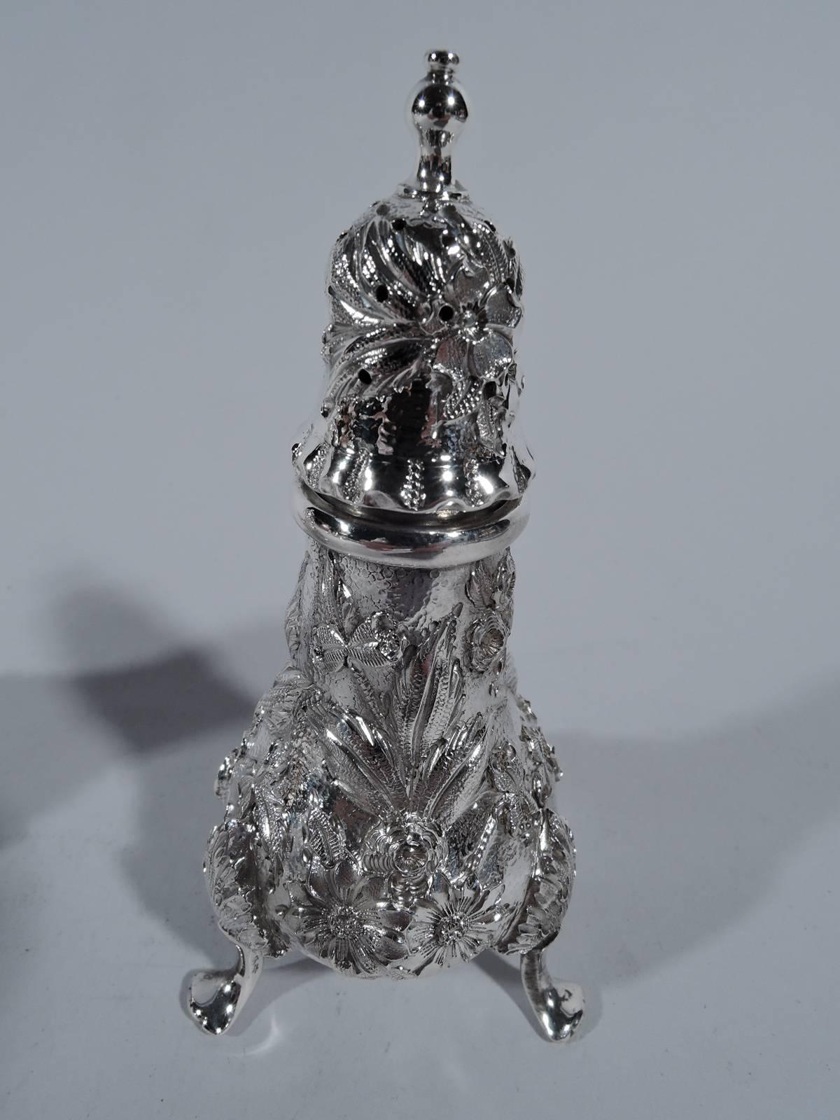 Pair of pretty repousse sterling silver salt and pepper shakers. Made by S. Kirk & Son Inc. in Baltimore, circa 1930. Each: Baluster body with pierced dome cover and three leaf-mounted supports. Floral repousse on stippled ground. Hallmark includes