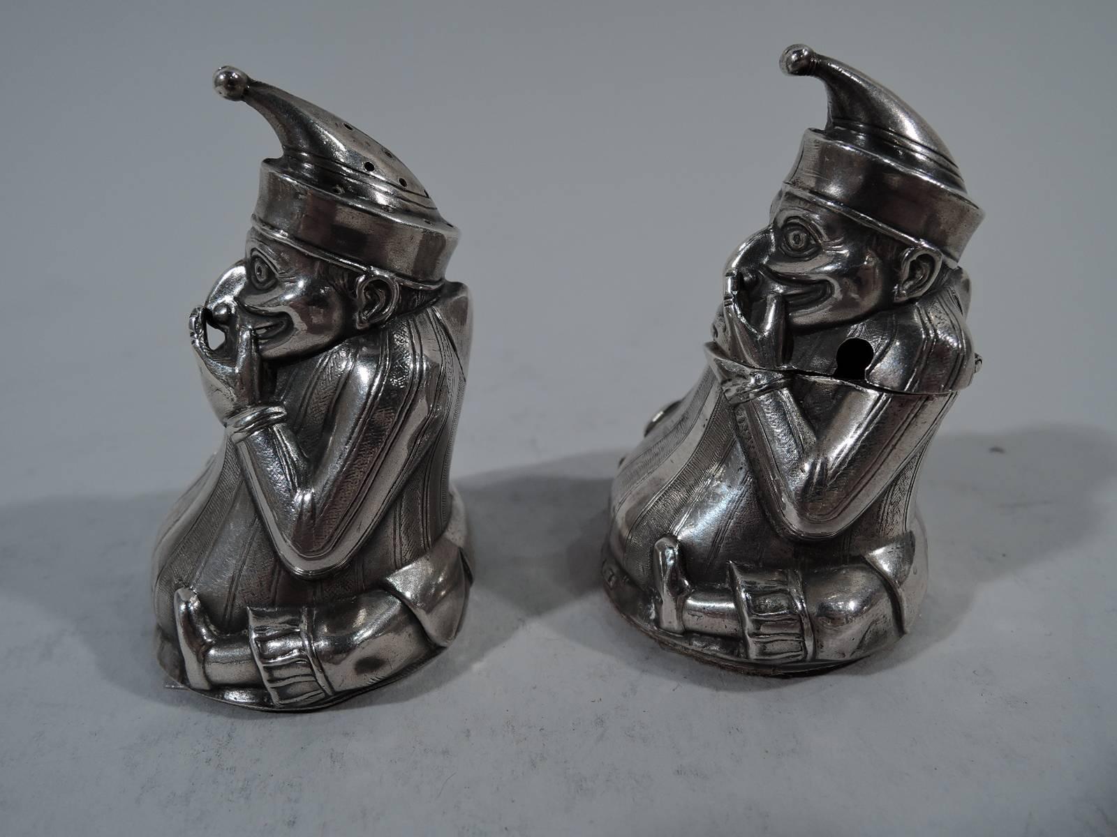 Pair of Edwardian figural sterling silver salt Shaker and mustard pot. Made by William Henry Sparrow in Birmingham in 1903. Each in form of seated Punch with legs wrapped around fat belly and finger touching hooked nose. Punch wears the traditional