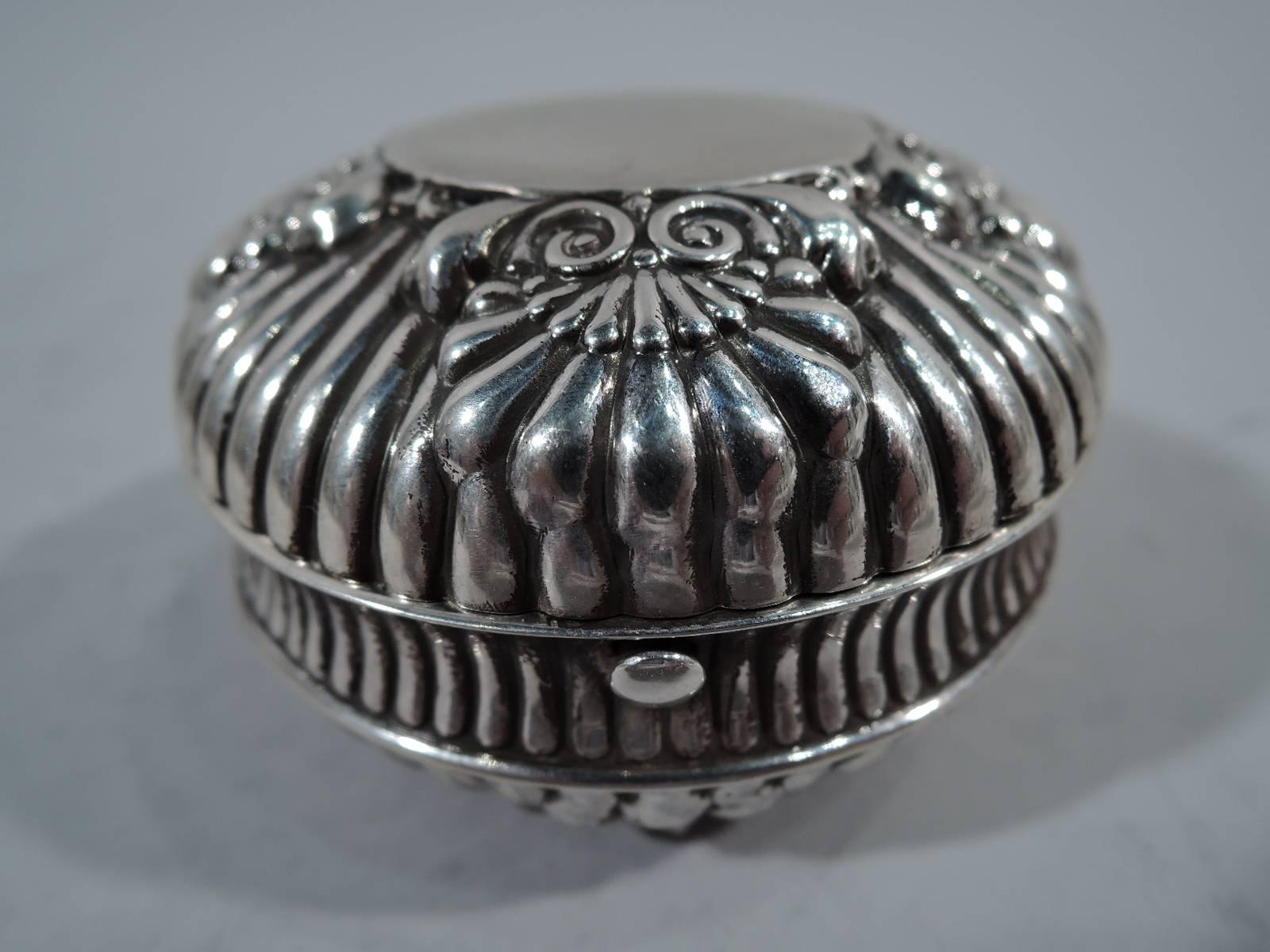 Sterling silver traveling inkwell. Made by Gorham in Providence in 1890. Round and lobed with stylized scallop shells. On top central circular frame (vacant). On bottom4 ball supports. Hinged cover. Interior has glass bottle with hinged cover.