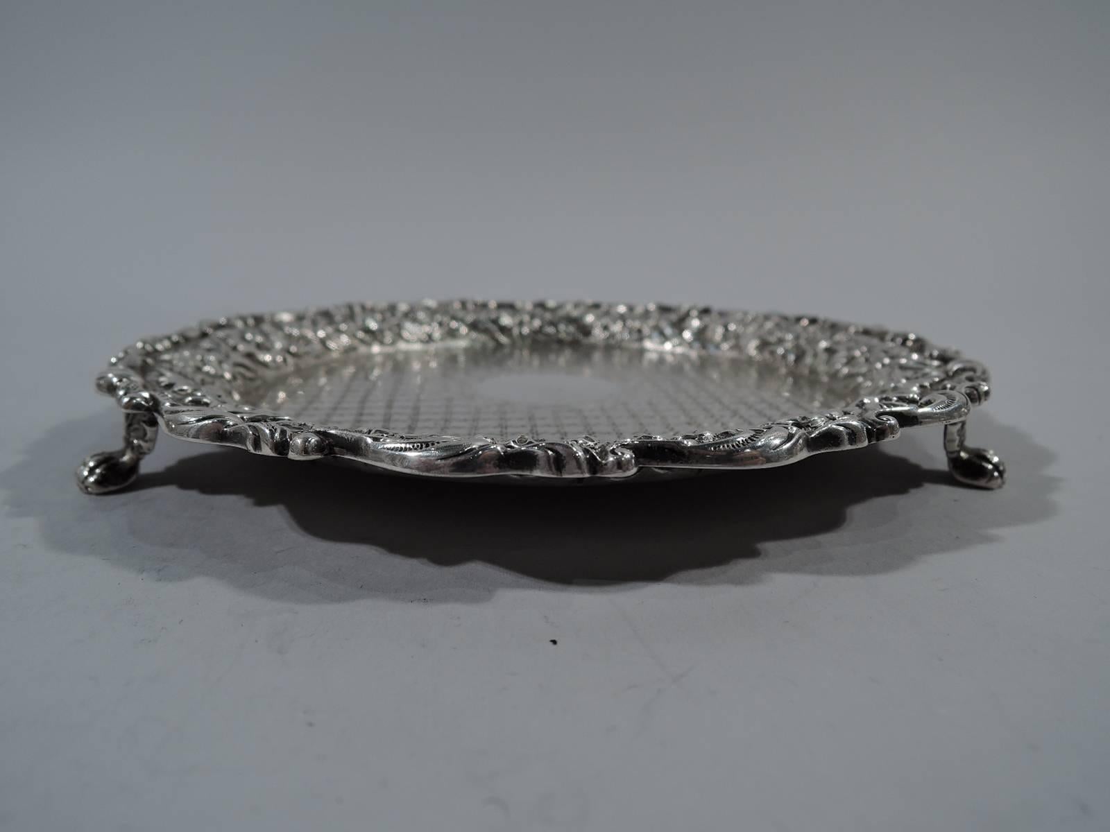 Sterling silver salver. Made by S. Kirk & Son Co. in Baltimore, circa 1910. Well has engraved diaper pattern with central wreath frame (vacant). Scrolled rim with repousse floral garland on stippled ground. Three paw supports. Measure: Weight 4.7