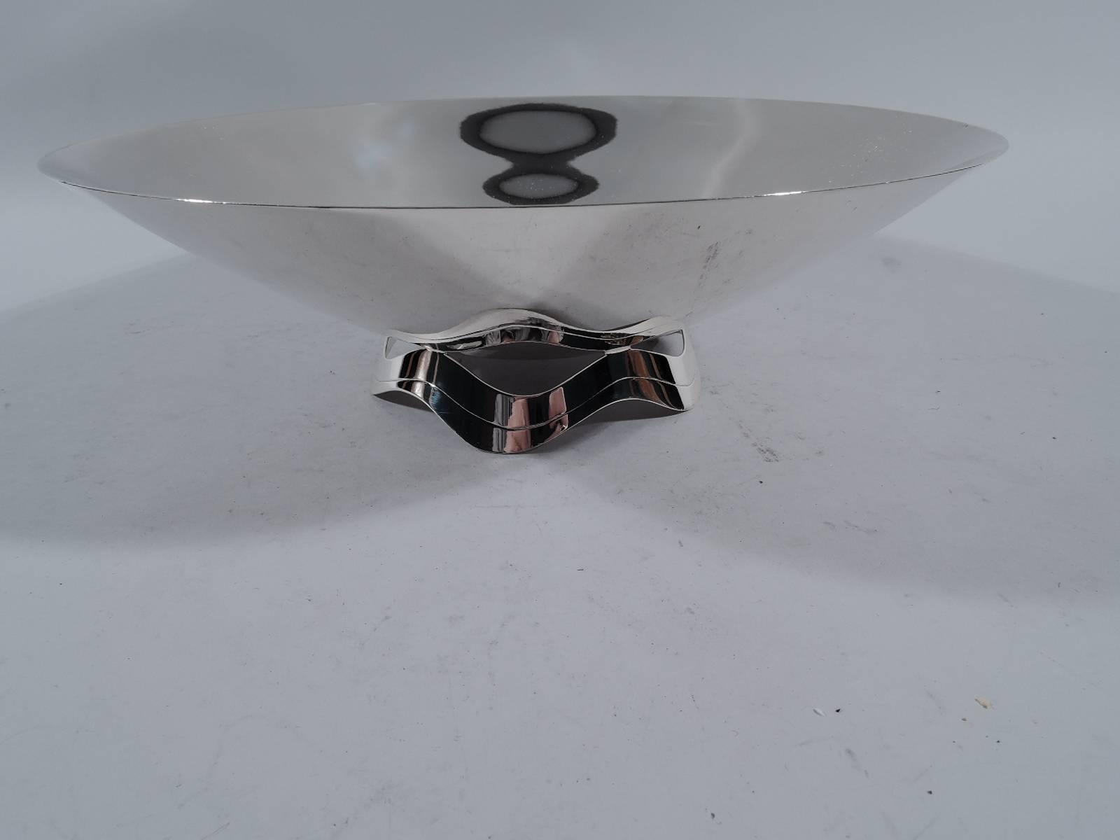 Mid-Century Modern sterling silver centerpiece bowl. Made by Tiffany & Co. in New York. Shallow bowl mounted to scrolled and open ribbon support. The support is reflected in the bowl – a witty example of reflection as a design element. Hallmark