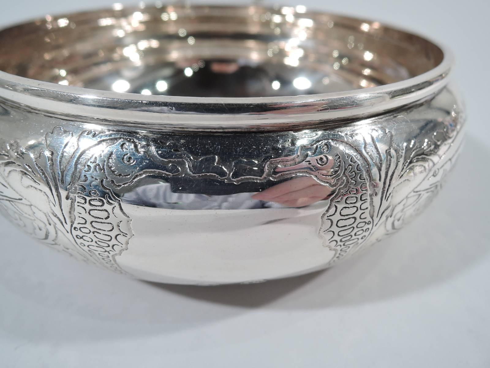 Sterling silver porringer with marine motif. Made by Tiffany & Co. in New York, circa 1910. Bellied bowl with acid-etched fish darting through wave-style rinceaux. Frame comprising two seahorses (vacant). Handle open with engraved leaves. Hallmark