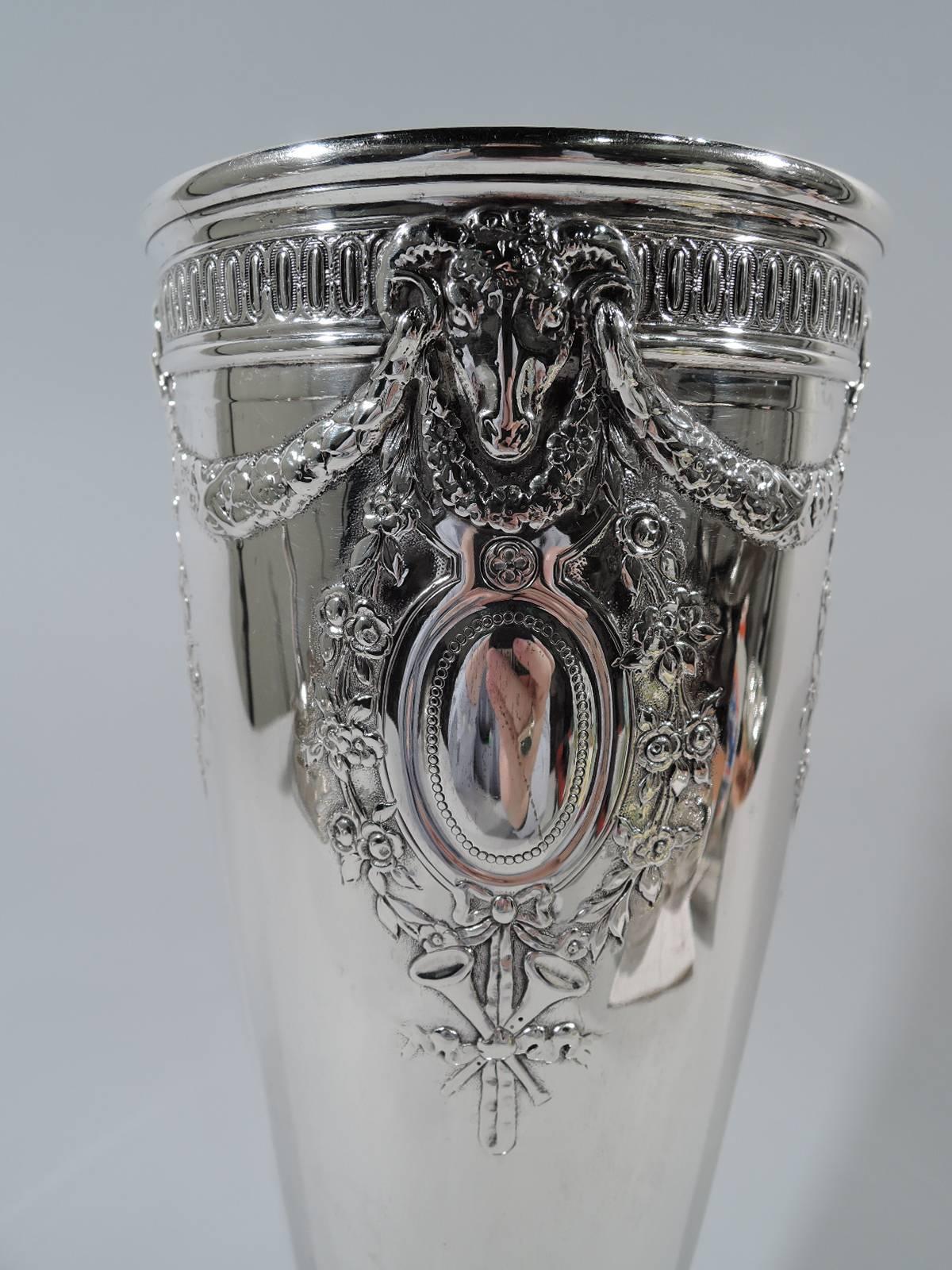 Edwardian sterling silver vase. Made by Tiffany & Co. in New York, circa 1914. Curved and tapering sides, lobed knop and stepped and raised foot. Chased, repousse and applied neoclassical ornament. At top is garland threaded through ram’s heads’