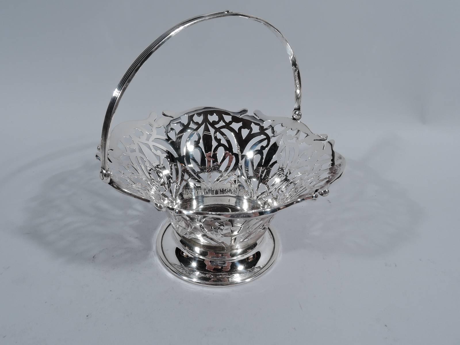 Pretty Edwardian sterling silver basket. Made by Frank W. Smith in Gardner, Mass., circa 1910. Circular solid well and flared and tapering sides with pierced abstract scrollwork. Reeded swing handle. Solid spread foot. Very sweet – a perfect hostess