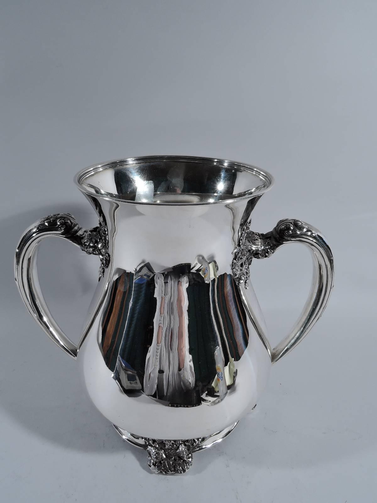 Sterling silver trophy cup. Made by Tiffany & Co. in New York, circa 1900. Ovoid body, flared mouth, and c-scroll handles with realistic leaf and bud mounts. Spread foot has same applied to four supports. Interior has gilt wash. A Fine design with