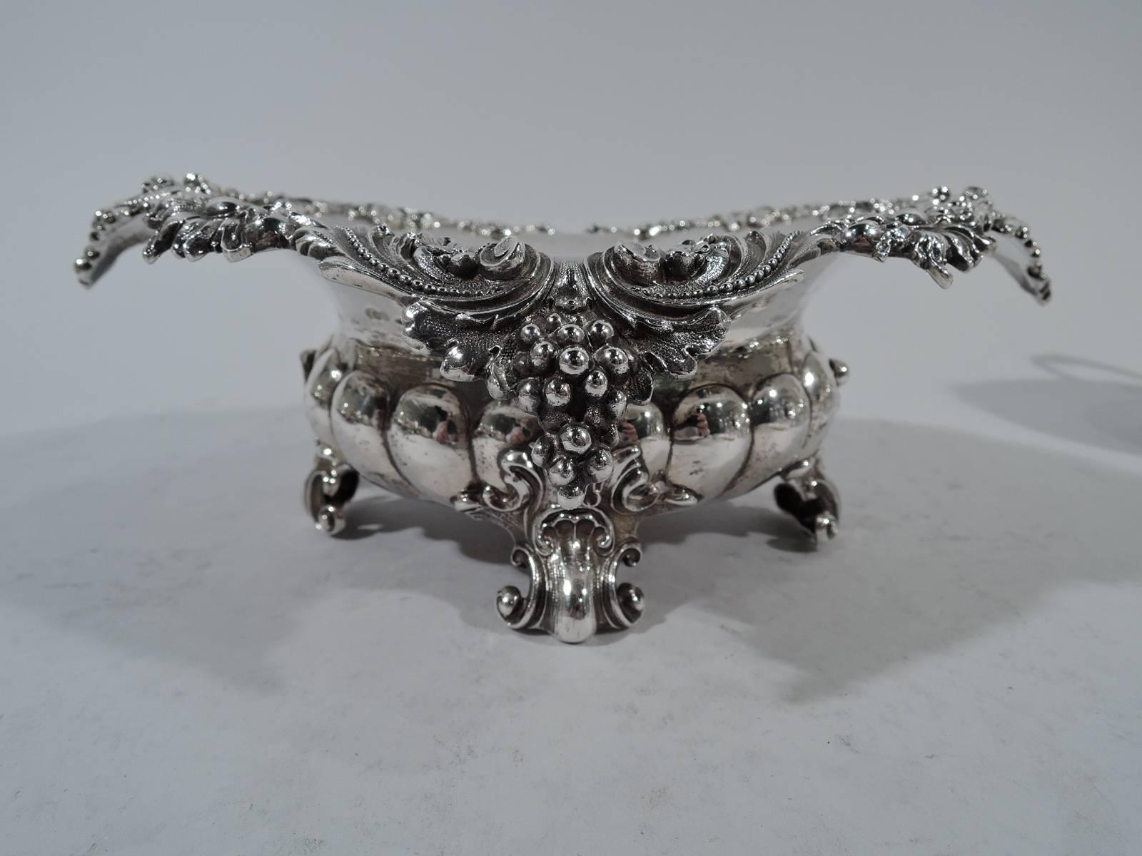 Pair of fancy sterling silver bowls. Made by Mauser in New York, circa 1890. Each: Lobed and bellied bowl on four leaf-mounted volute scrolls. Raised and turned-down quatrefoil rim with applied scrolls, flowers, and grape bunches. Hallmarked. Total
