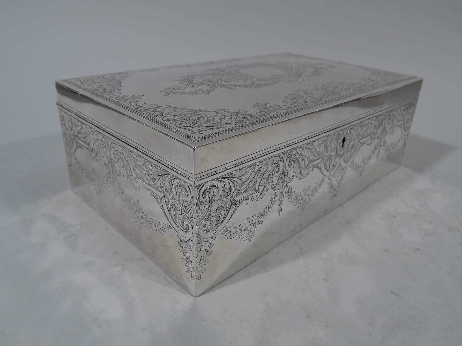 Edwardian sterling silver humidor. Made by Howard & Co. in New York in 1901. Rectangular with straight sides. Cover hinged and flat. Engraved scrolls, shells, and garlands. Cover top has central scrolled frame (vacant). Wavy ornament on cover