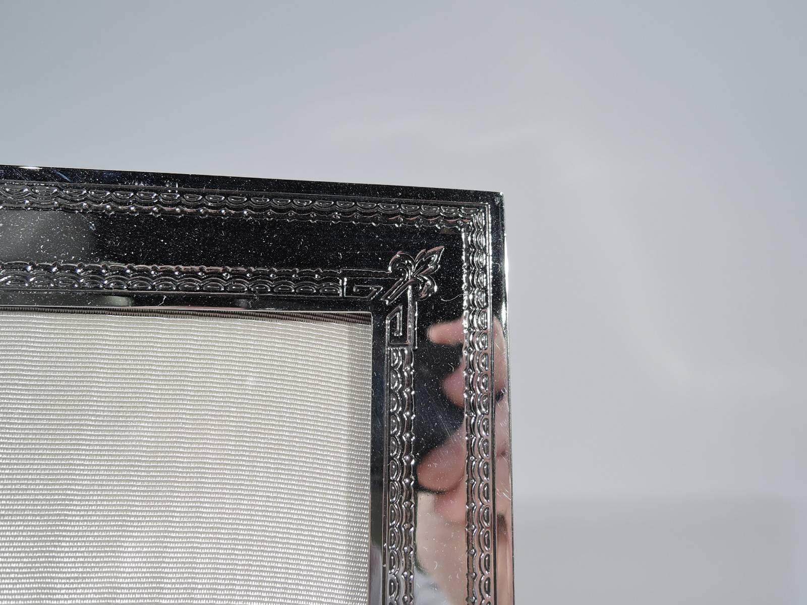 Edwardian sterling silver picture frame. Made by Eleder-Hickok (formerly Lebkuecher) in Newark, circa 1915. Rectangular with acid-etched ornamental borders and stylized flowers and leaves. Trapezoidal cartouche (vacant). With glass, silk lining and