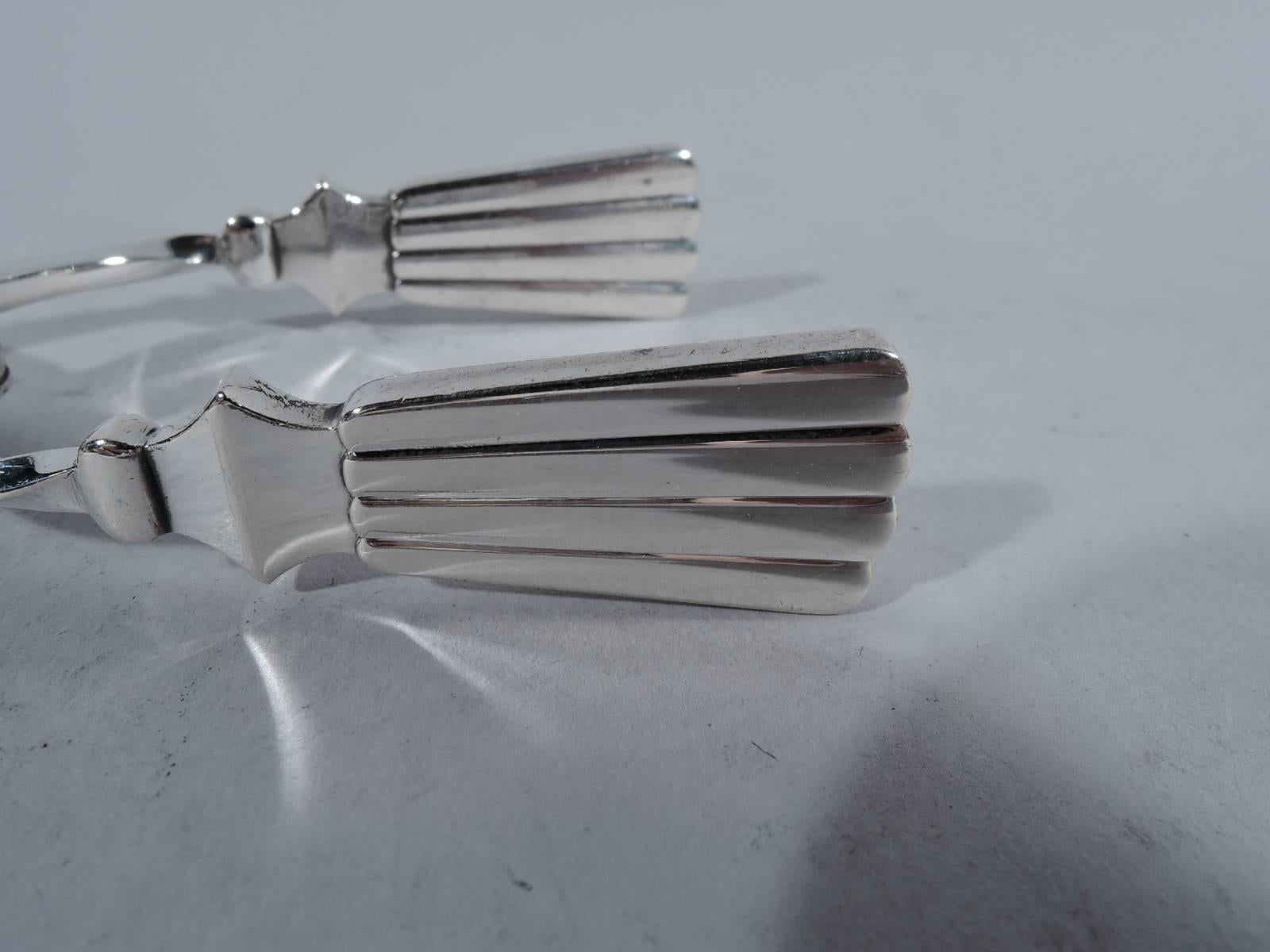 Pair of sterling silver ice tongs in Bernadotte pattern. Made by Georg Jensen in Copenhagen. Tapering linear terminals and leaf jaws. The pattern was first produced in 1939. Postwar hallmark. Weight: 2.3 troy ounces.