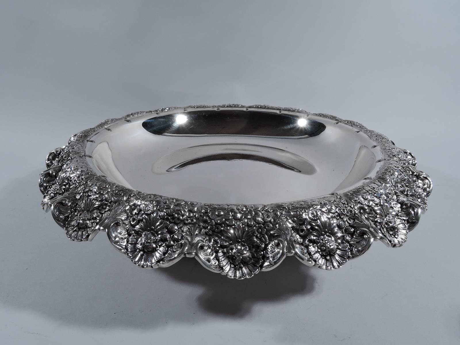 Rare sterling silver centrepiece bowl with wonderful wildflowers. Made by Tiffany & Co. in New York, circa 1894. Shallow bowl on raised foot ring with four leaf-mounted paws. Rim turned down and crimped with dense and overlapping flowers, including