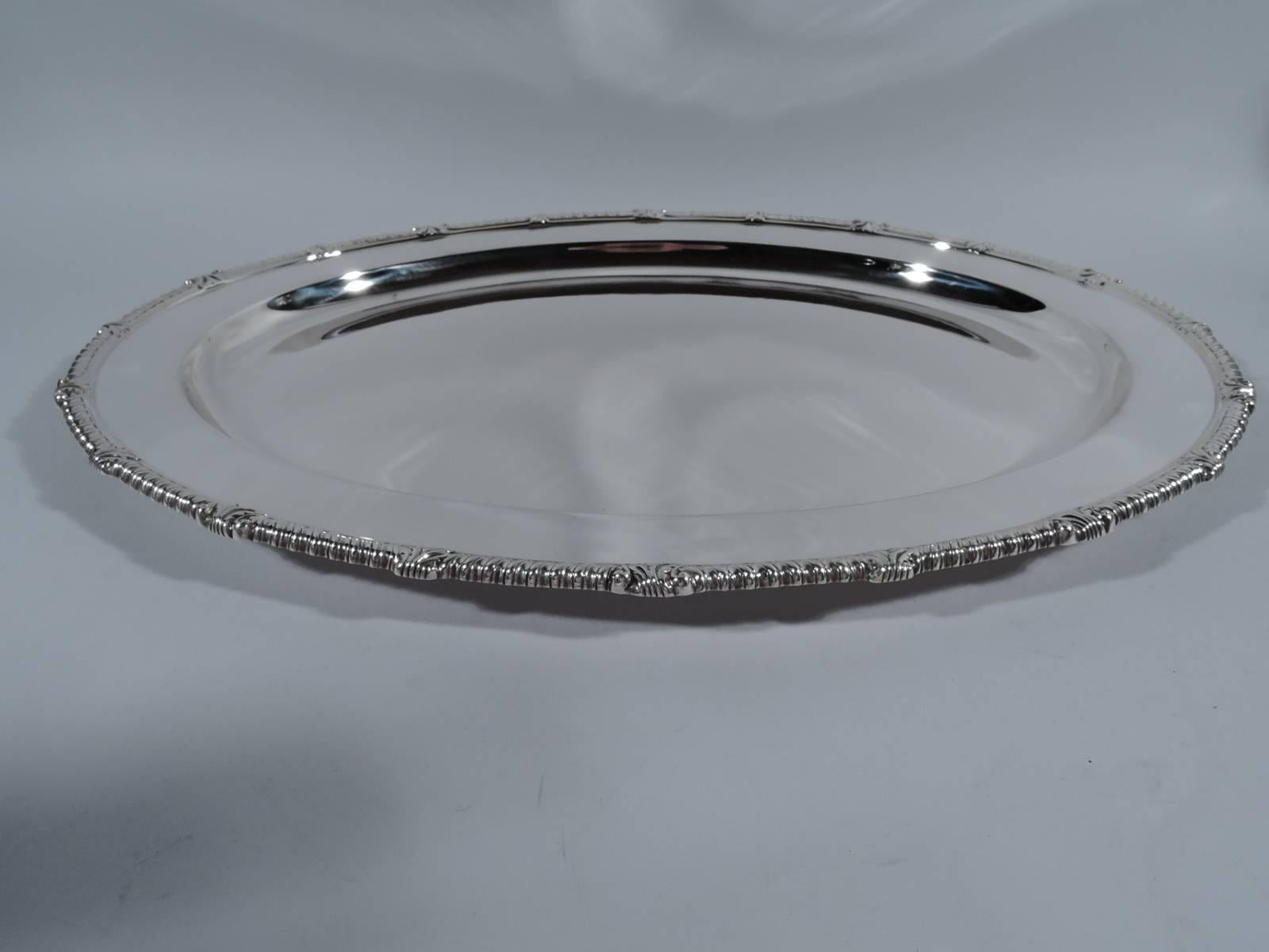 Georgian-style serving tray. Made by Tiffany & Co. in New York. Oval with well. Rim gadrooned with leaves. Hallmark includes postwar pattern no. 23818. Weight: 63 troy ounces.