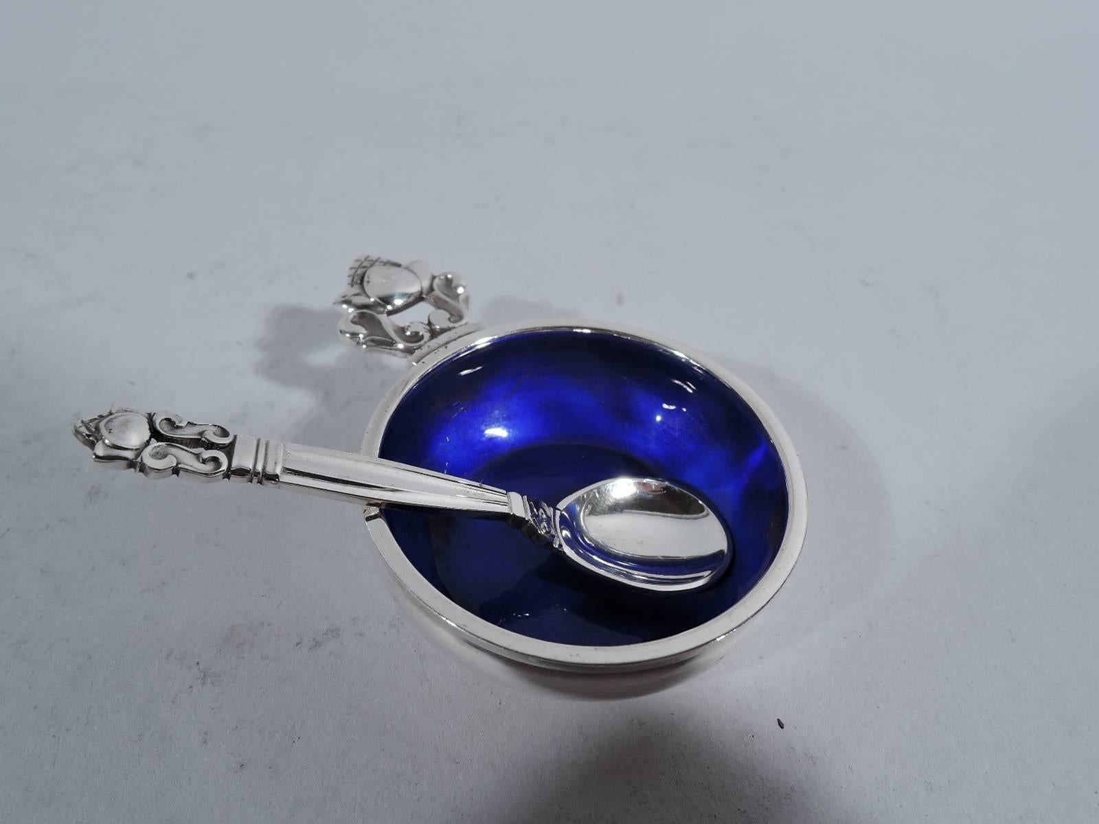 Set of four sterling silver and enamel open salts and spoons in Acorn pattern. Made by Georg Jensen in Copenhagen. Each salt: Bowl with curved sides, cobalt enameled interior, and stylized acorn handle. Each spoon: Fluted stem, oval bowl, and