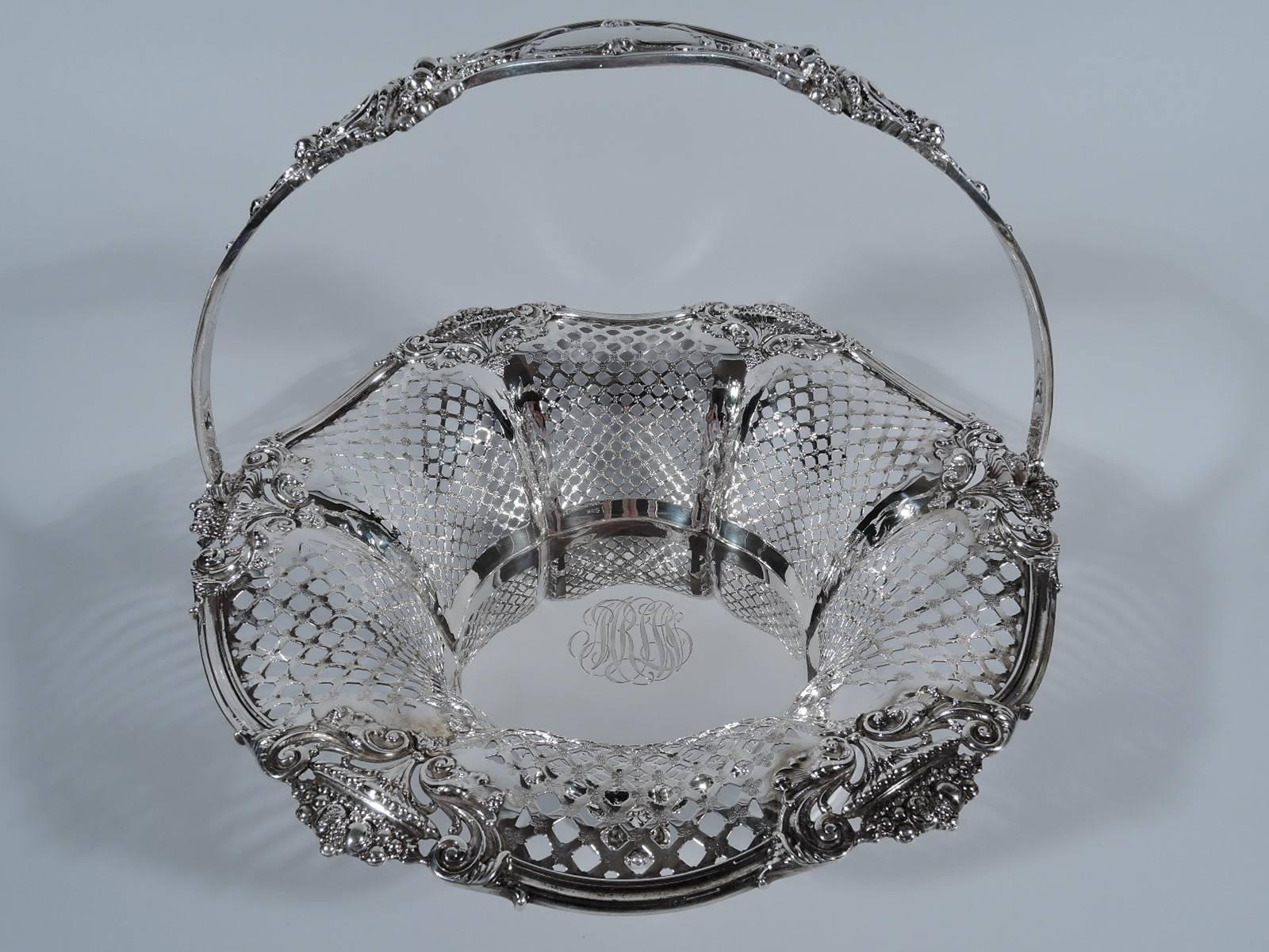 Edwardian sterling silver basket. Made by Black, Starr & Frost in New York, circa 1910. Solid and round shaped well engraved with interlaced script monogram. Flared sides with pierced diaper ornament. Molded wavy rim with cornucopias. Pierced swing