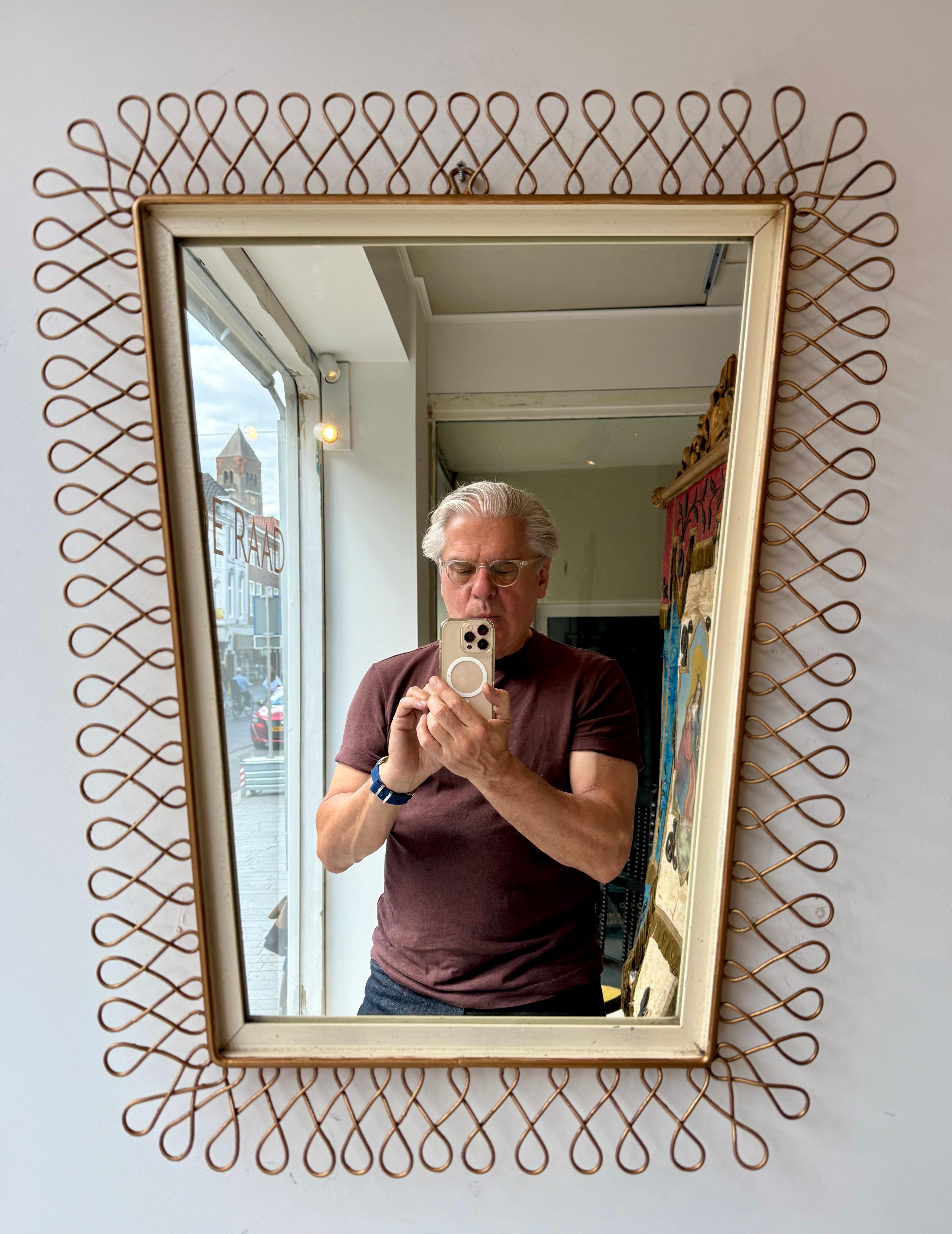 Square mirror featuring a slightly tapered frame, designed in the style of Josef Frank. Gold loops are encircling the mirror.