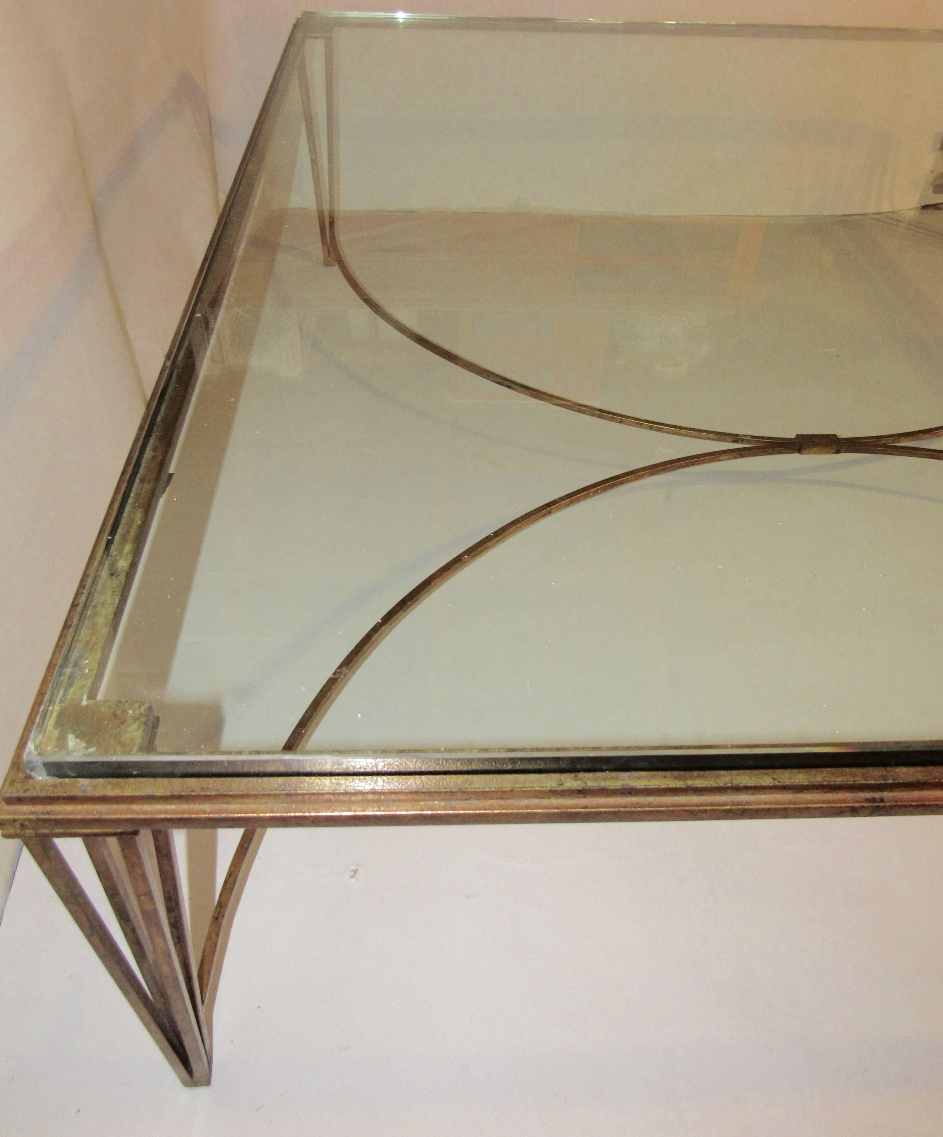 Classic elegant French gilt iron coffee table with a 3/4 inch thick  glass inset top. The frame is in excellent vintage condition. We have filled chips in the vintage glass but are happy to order a new piece if you desire.