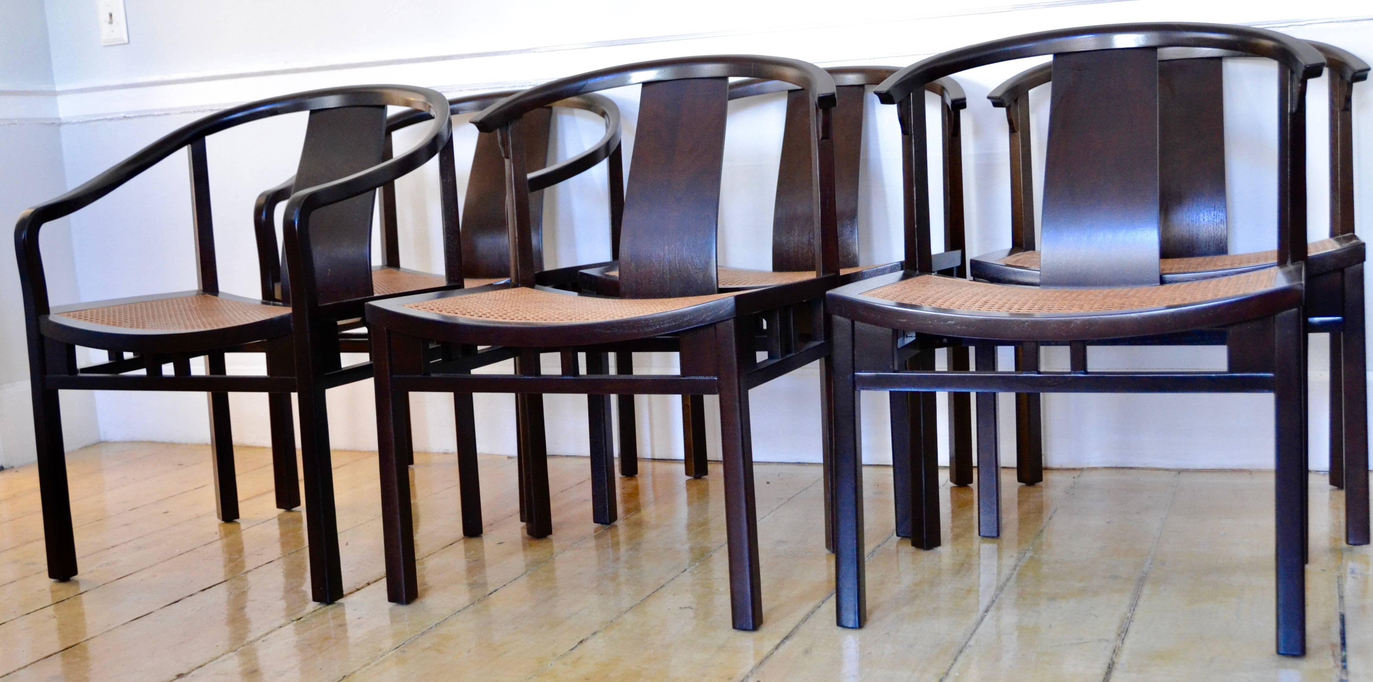 Michael Taylor suite of six dining chairs (two-arm and four sides) with caned seats  are from the Baker Far East collection designed in the early 1950s. 
The chair frames, caning, and vintage seat cushions are in excellent condition. 