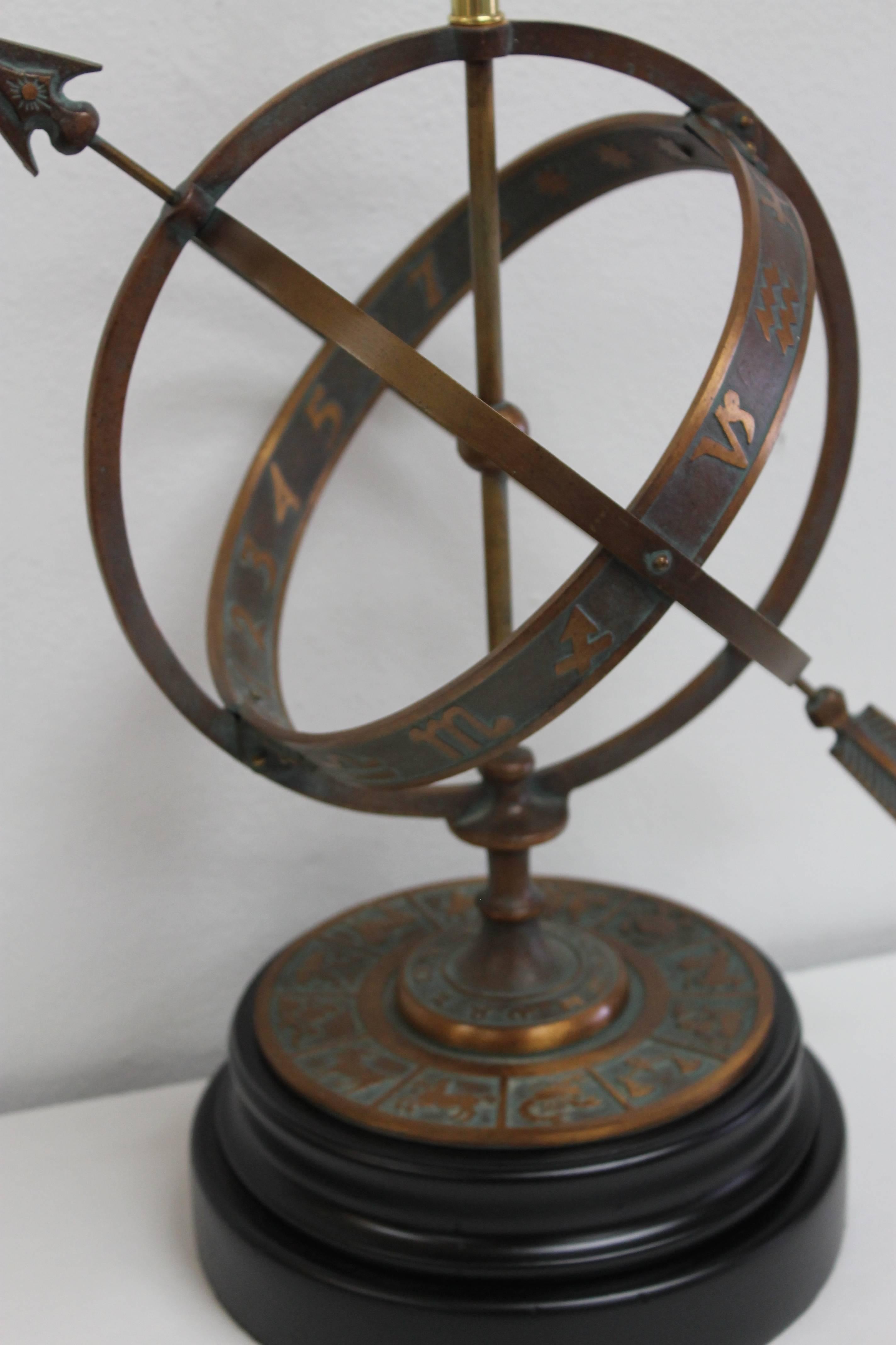 A bronze sundial table lamp in the form of zodiac signs with stylistic piercing arrow by Frederick Cooper, Chicago. This lamp has a beautiful greenish/verdigris patina. Measures: Base is 10" diameter. Total height is 22" from base to the